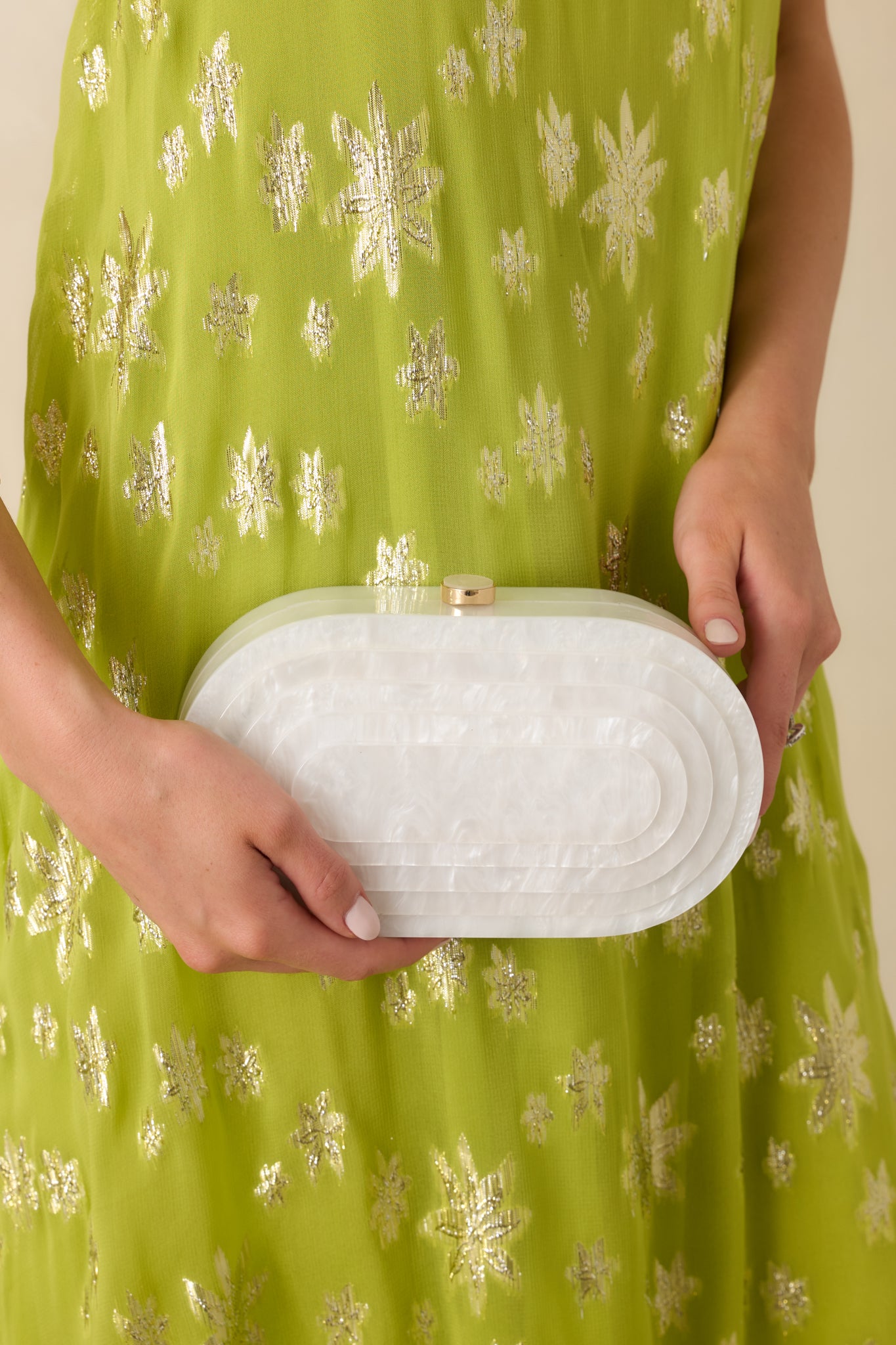 Close view of the white pearlescent clutch highlighting the smooth luminous surface and elegant oval shape.