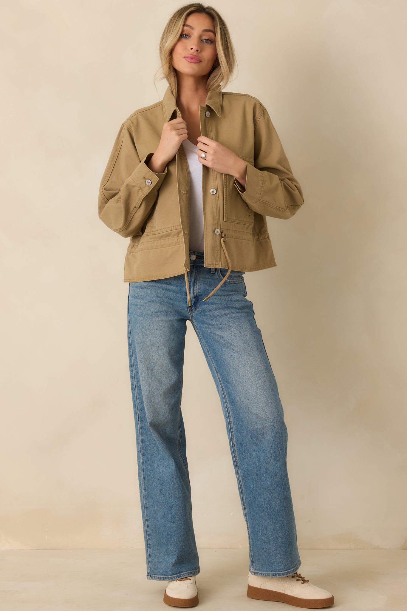 Front view of tan jacket featuring adjustable drawcord hem, button cuffs, and relaxed woven silhouette.