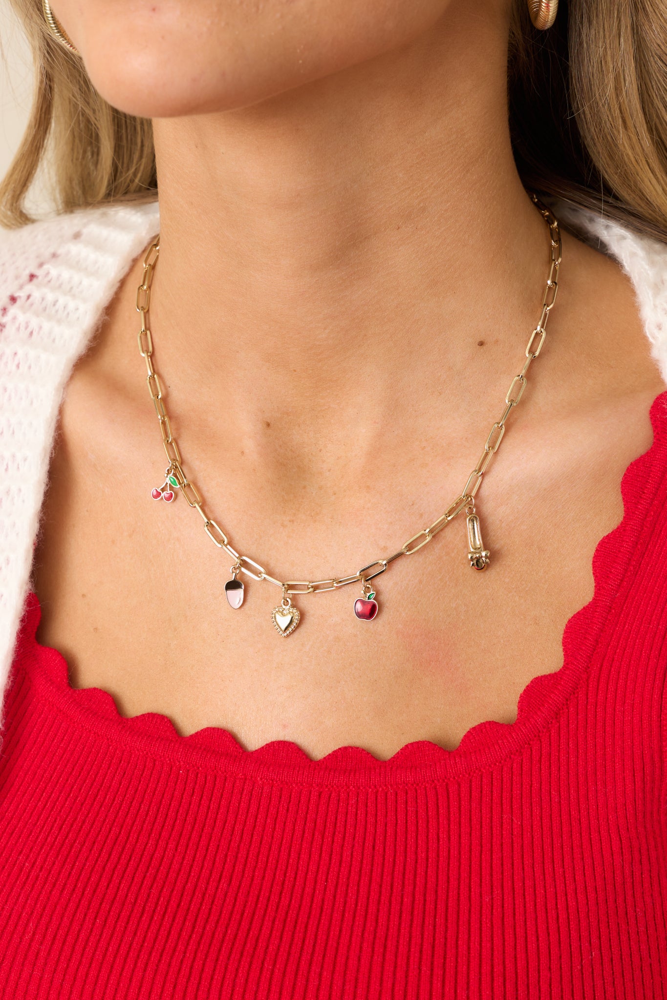 A gold charm necklace featuring a rectangular chain adorned with a variety of small gold charms and a lobster claw closure.