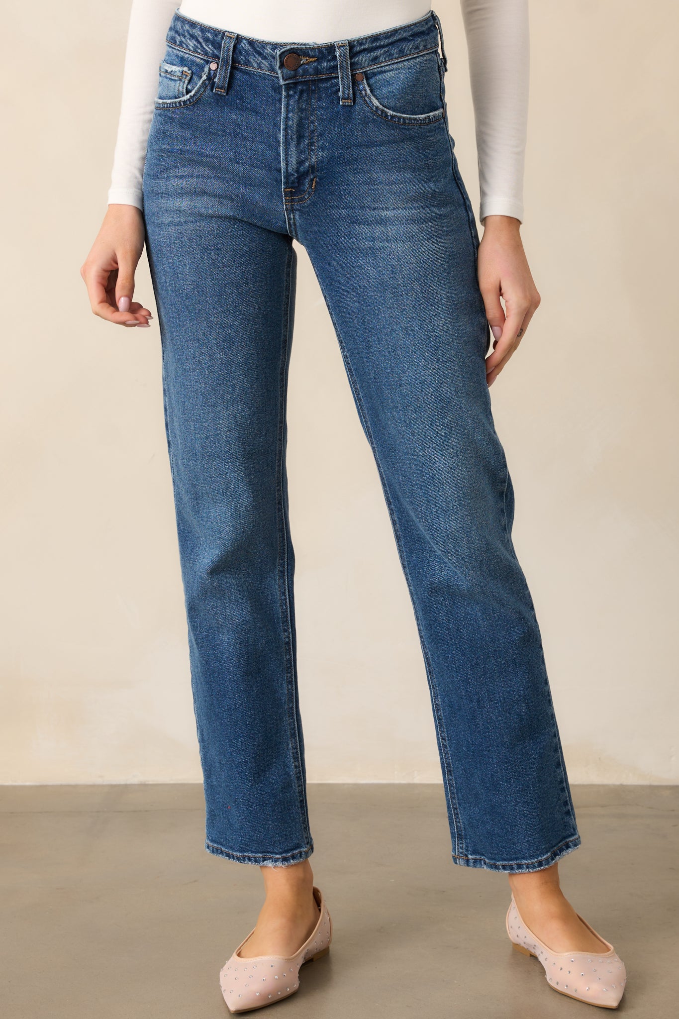 Cropped view of dark wash jeans focusing on the high-waisted waistband with visible belt loops.