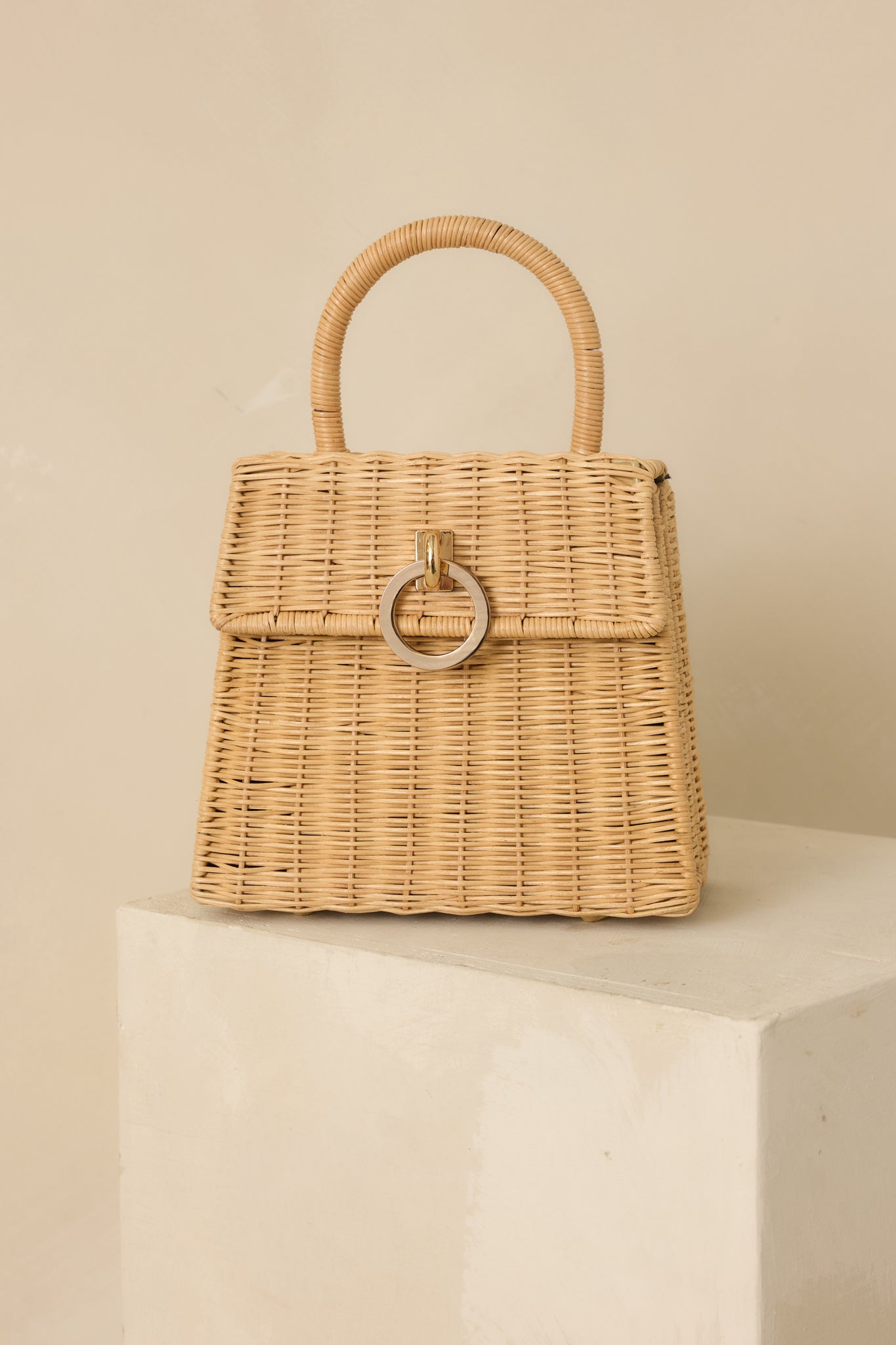 Detailed close-up of the natural woven handbag focusing on the woven texture, structured top handle, and fabric-lined expandable sides.