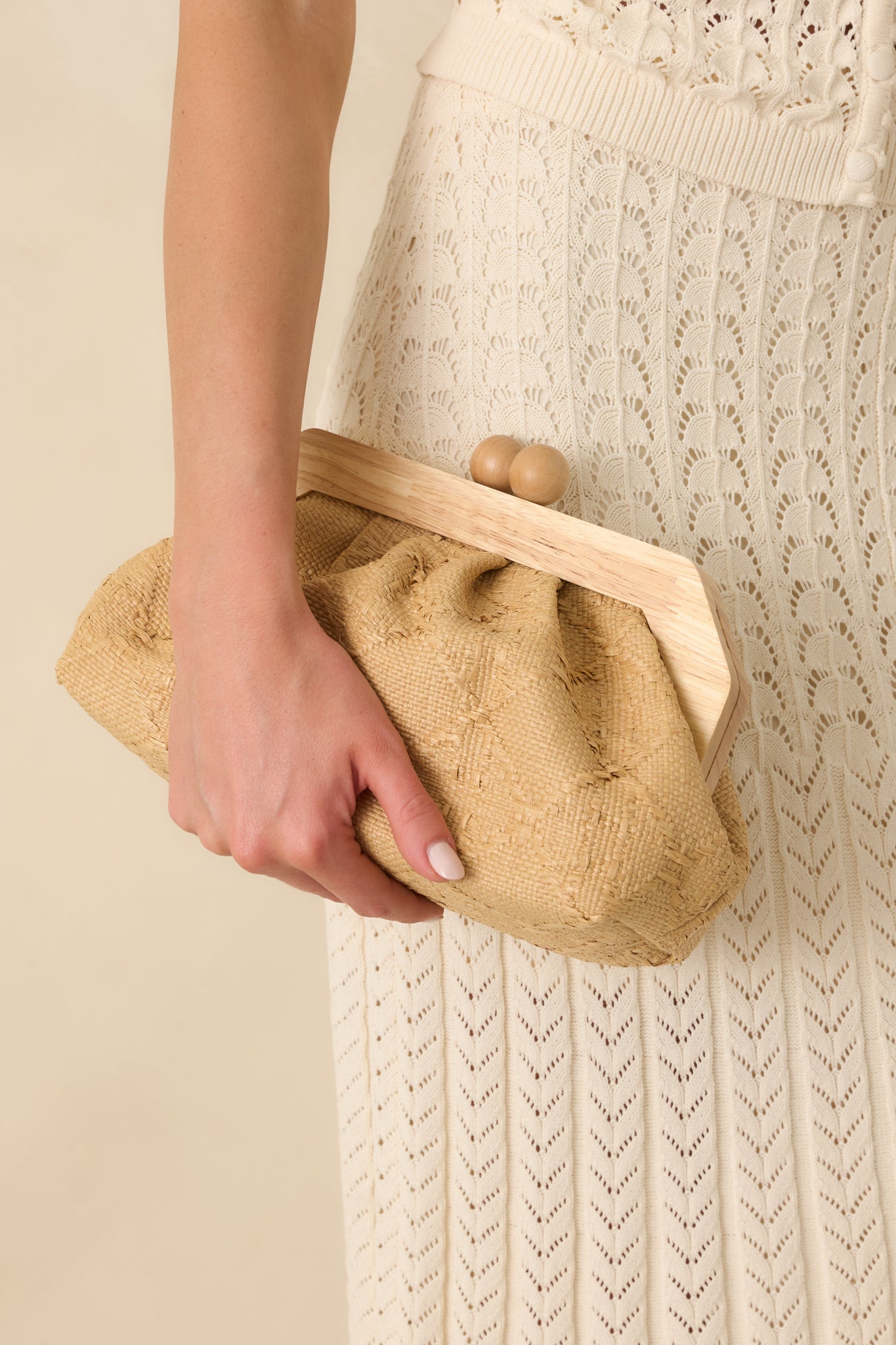 Cropped front view emphasizing the woven texture, wooden frame, and magnetic clasp closure of the clutch.