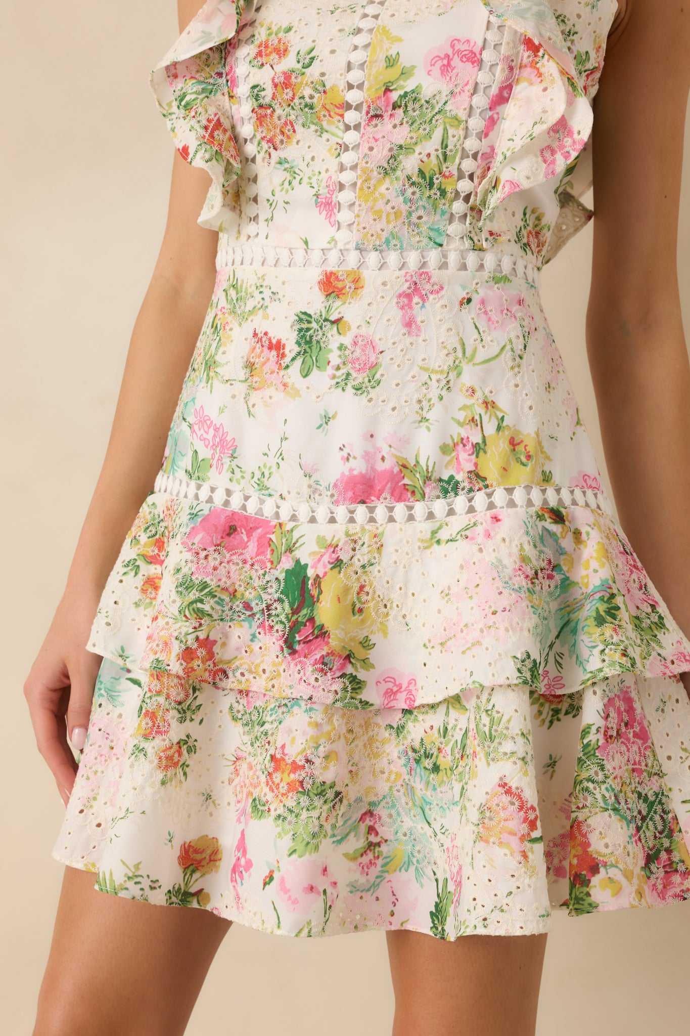 Close-up of ivory mini dress showing eyelet embroidery details, floral print, and ruffle edging.
