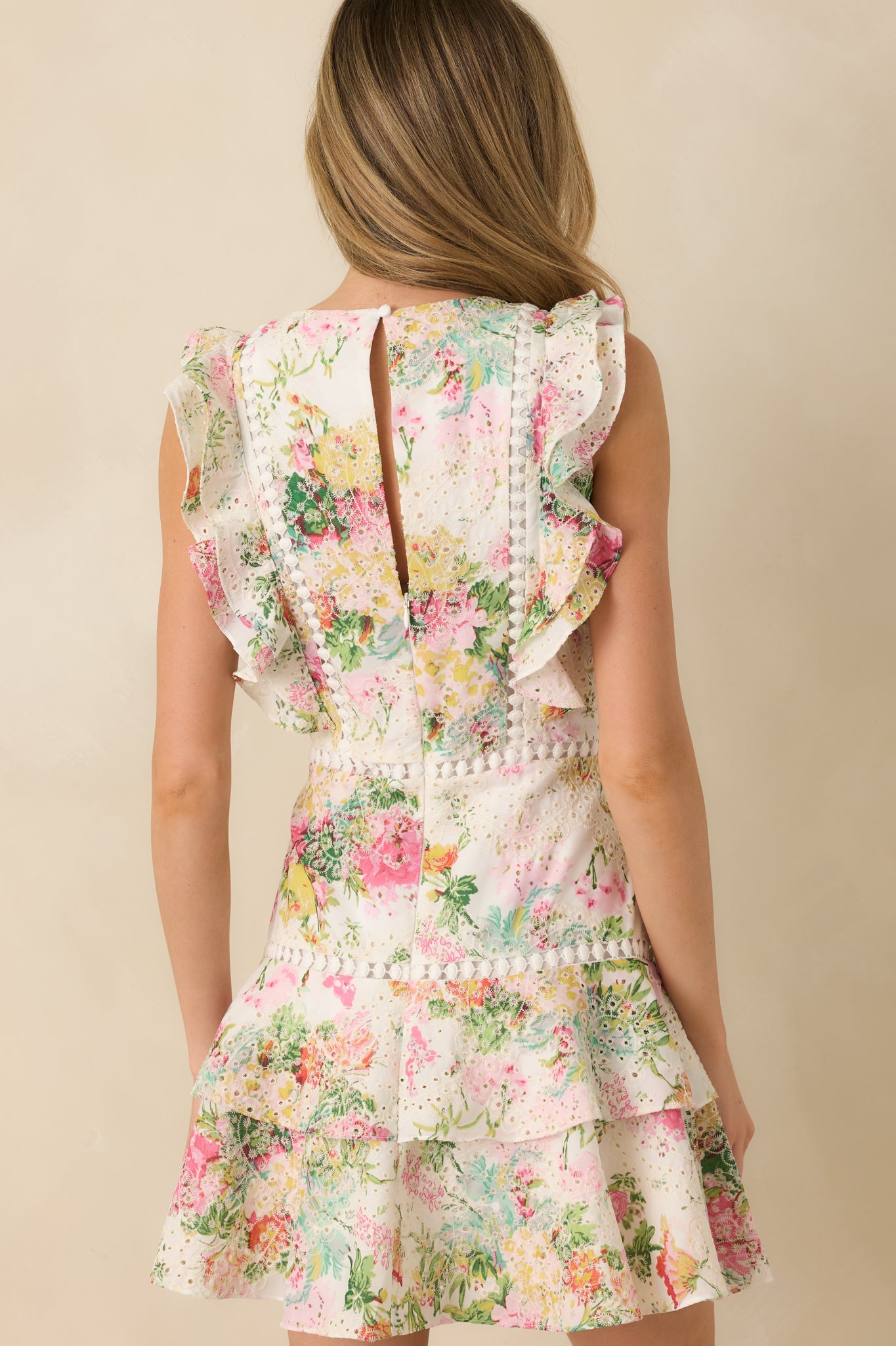 Rear view of ivory floral mini dress highlighting back zipper, keyhole closure, and sleeveless design.
