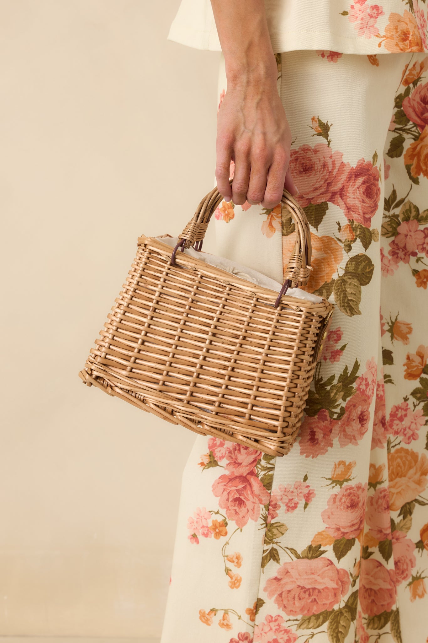 Handbag with a wicker-like woven design, functional top handles, and a drawstring closure, finished with a removable faux pearl strap for decorative detail.