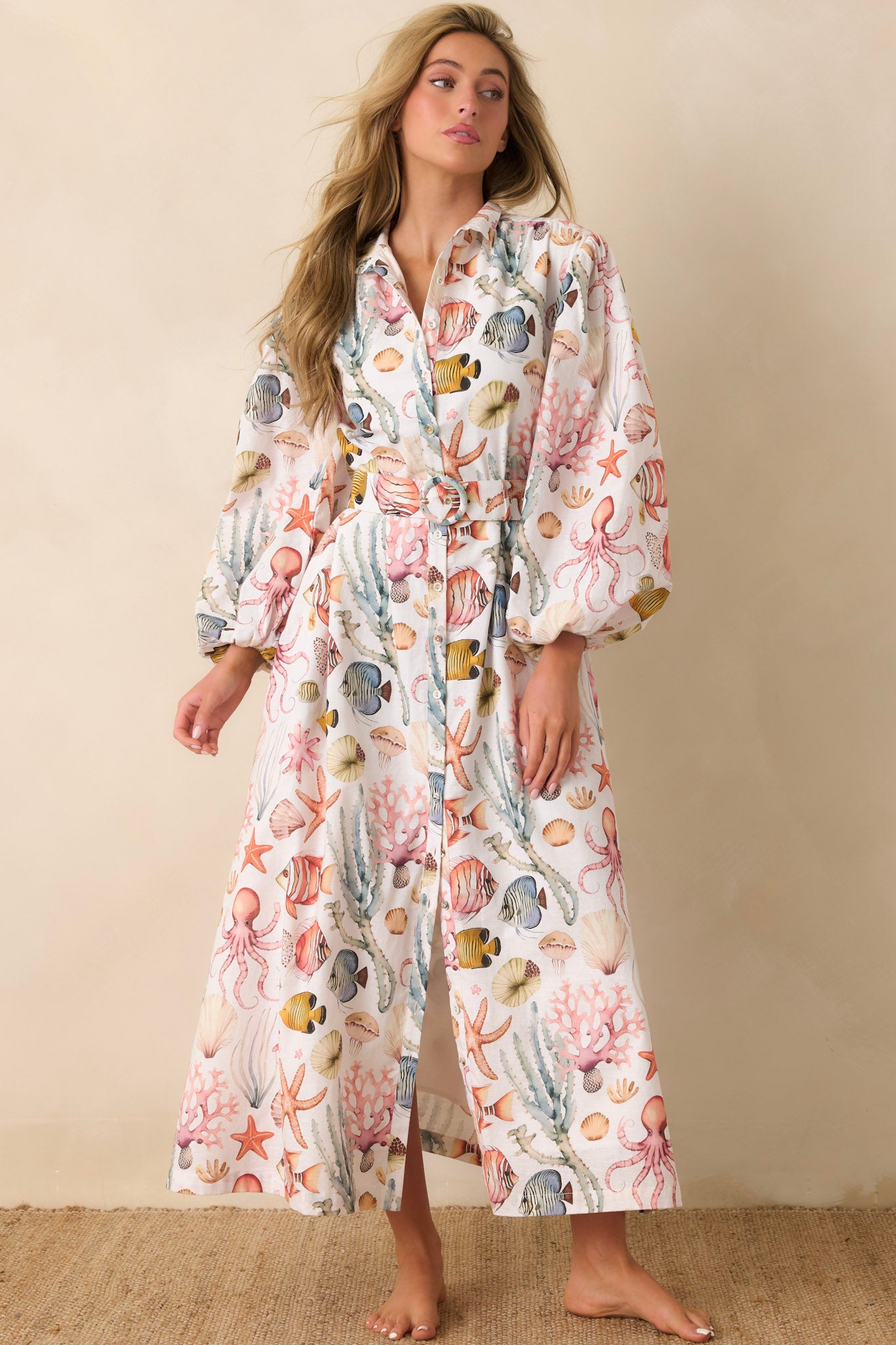 Woman wearing a sea creature patterned maxi dress against a beige background.