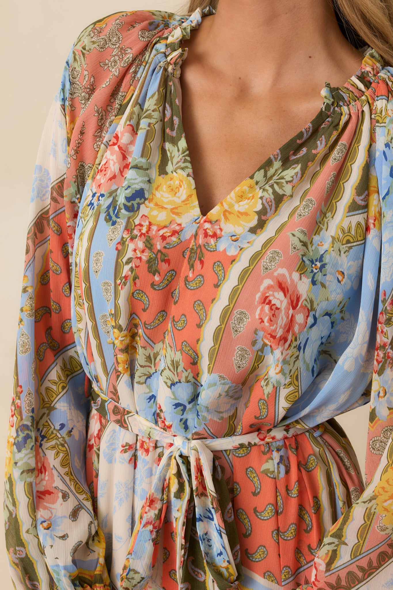 Close-up of dress showing ruffled collar, elastic cuffs, self-tie belt, and floral print texture.