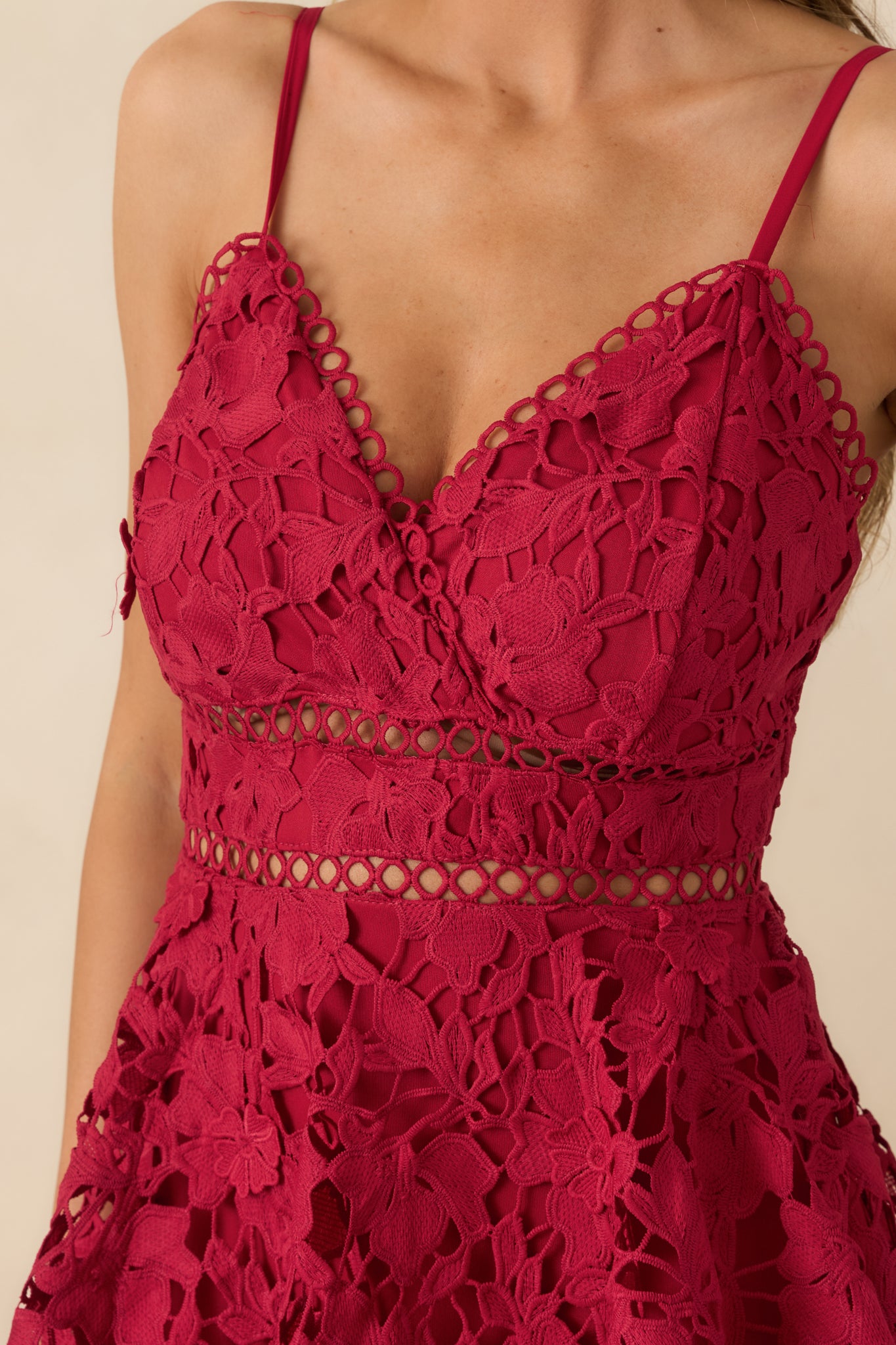 Close-up of red maxi dress showing floral lace overlay, ladder-lace waist detail, and spaghetti straps.