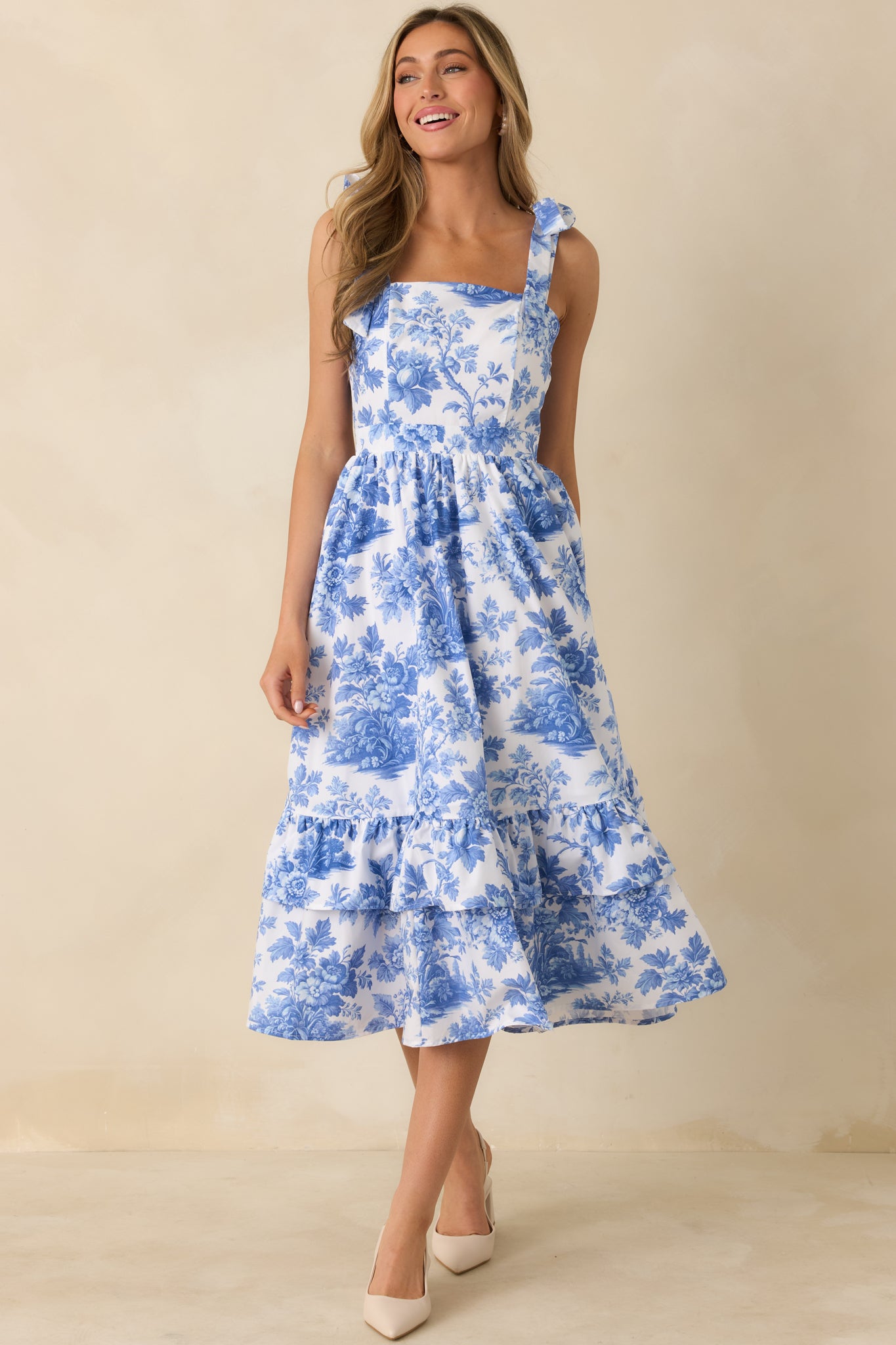 Cotton floral midi dress showcasing a square neckline, delicate bow straps, and a flowing tiered silhouette.