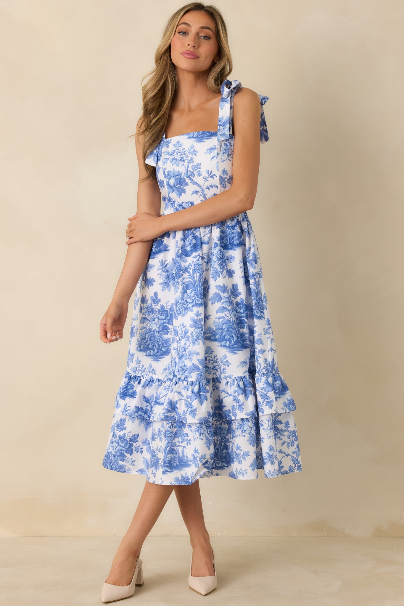 Blue and white midi dress with a romantic floral pattern, fitted bodice, and softly layered tiered skirt.