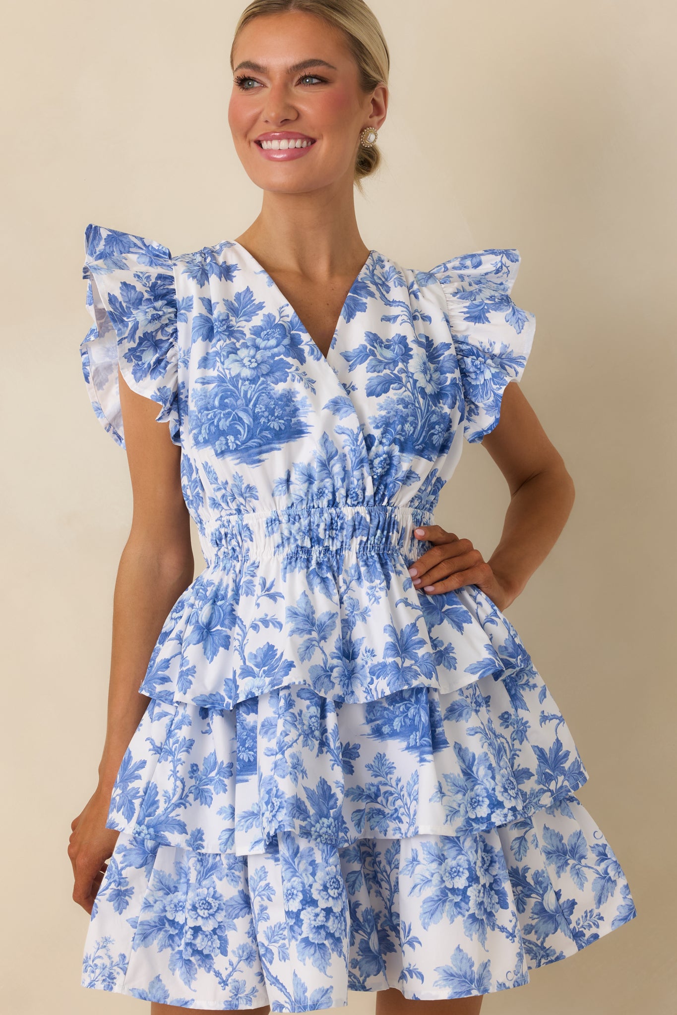 Focus on the tiered skirt, smocked bodice, and lightweight woven fabric of the blue floral mini dress.