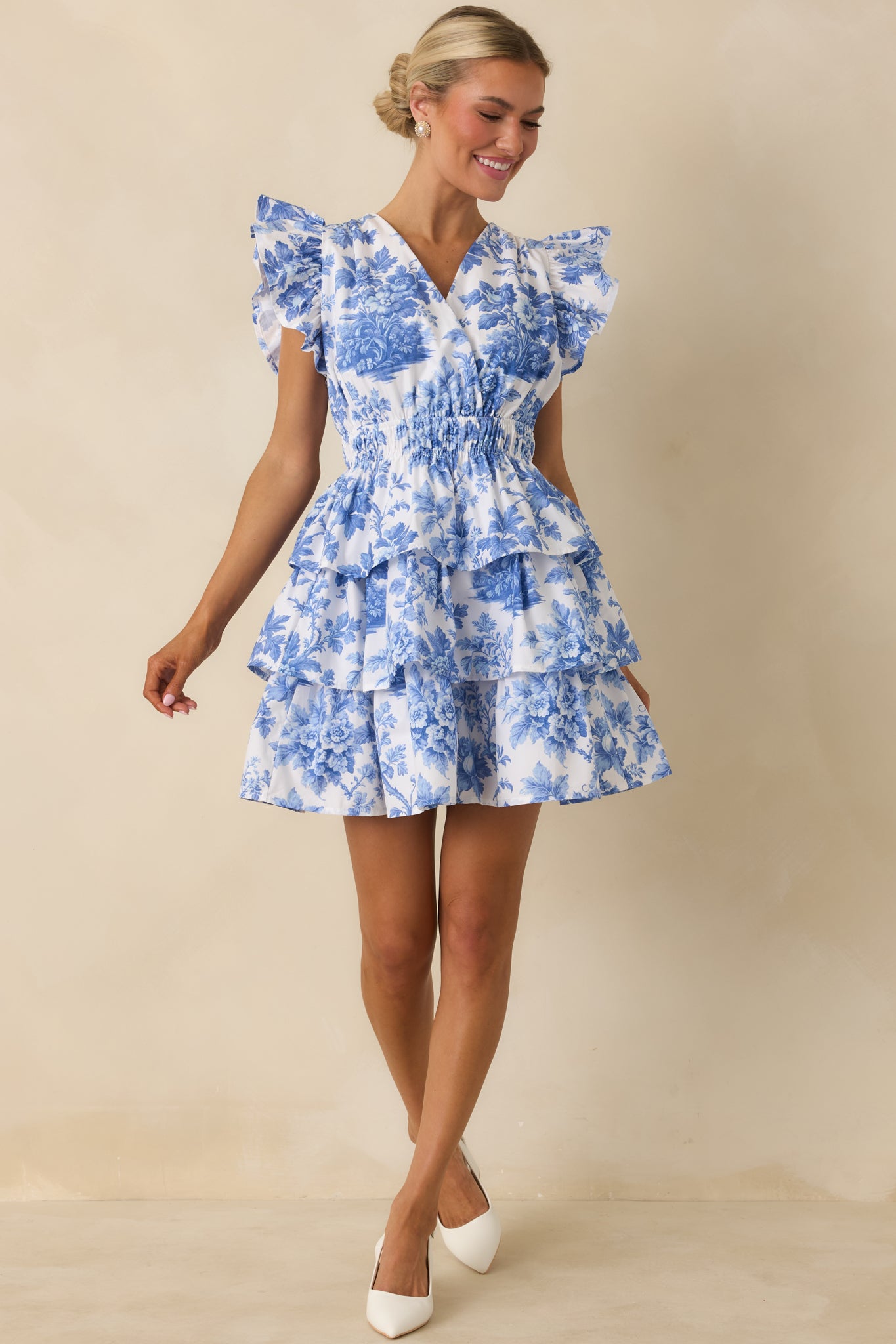 Flowing blue floral mini dress with smocked waist, flutter sleeves, and airy tiered skirt for easy movement.