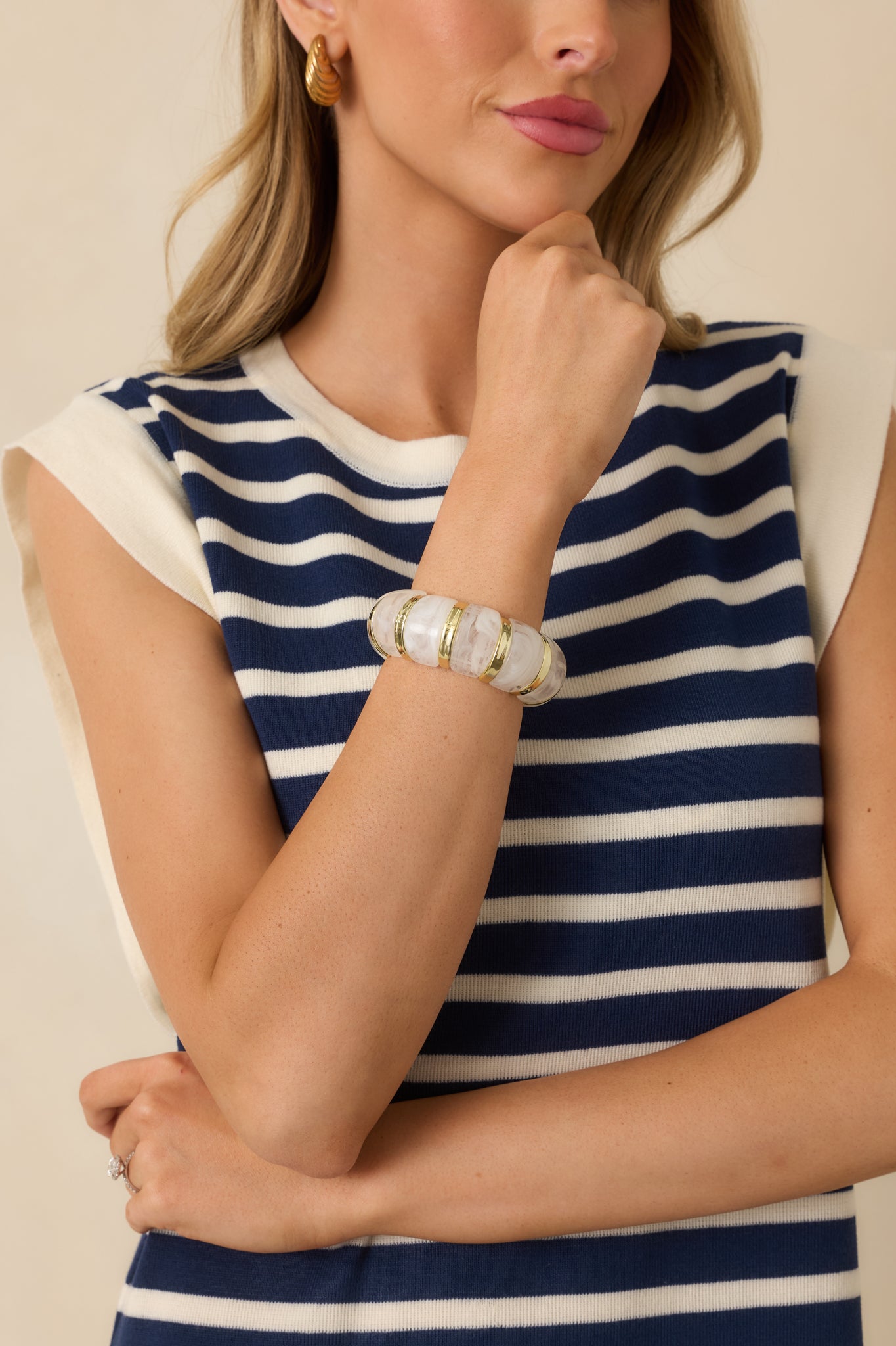 Cropped view of a gold bracelet featuring smooth, rounded settings arranged along a flexible stretch band.