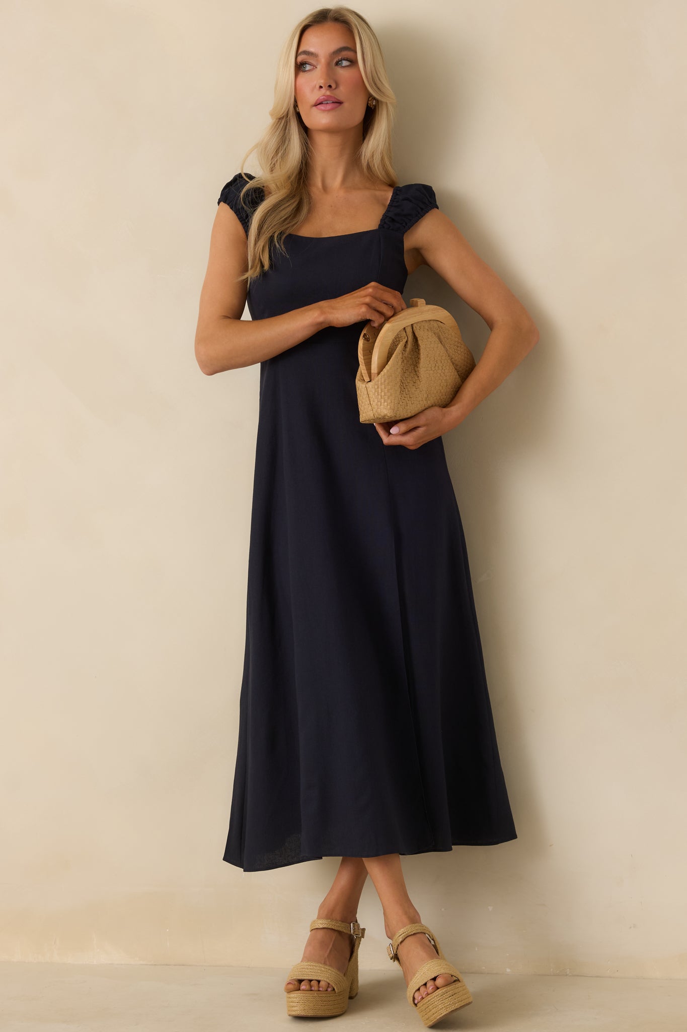 Full body view of the navy dress featuring its square neckline and midi-length design.