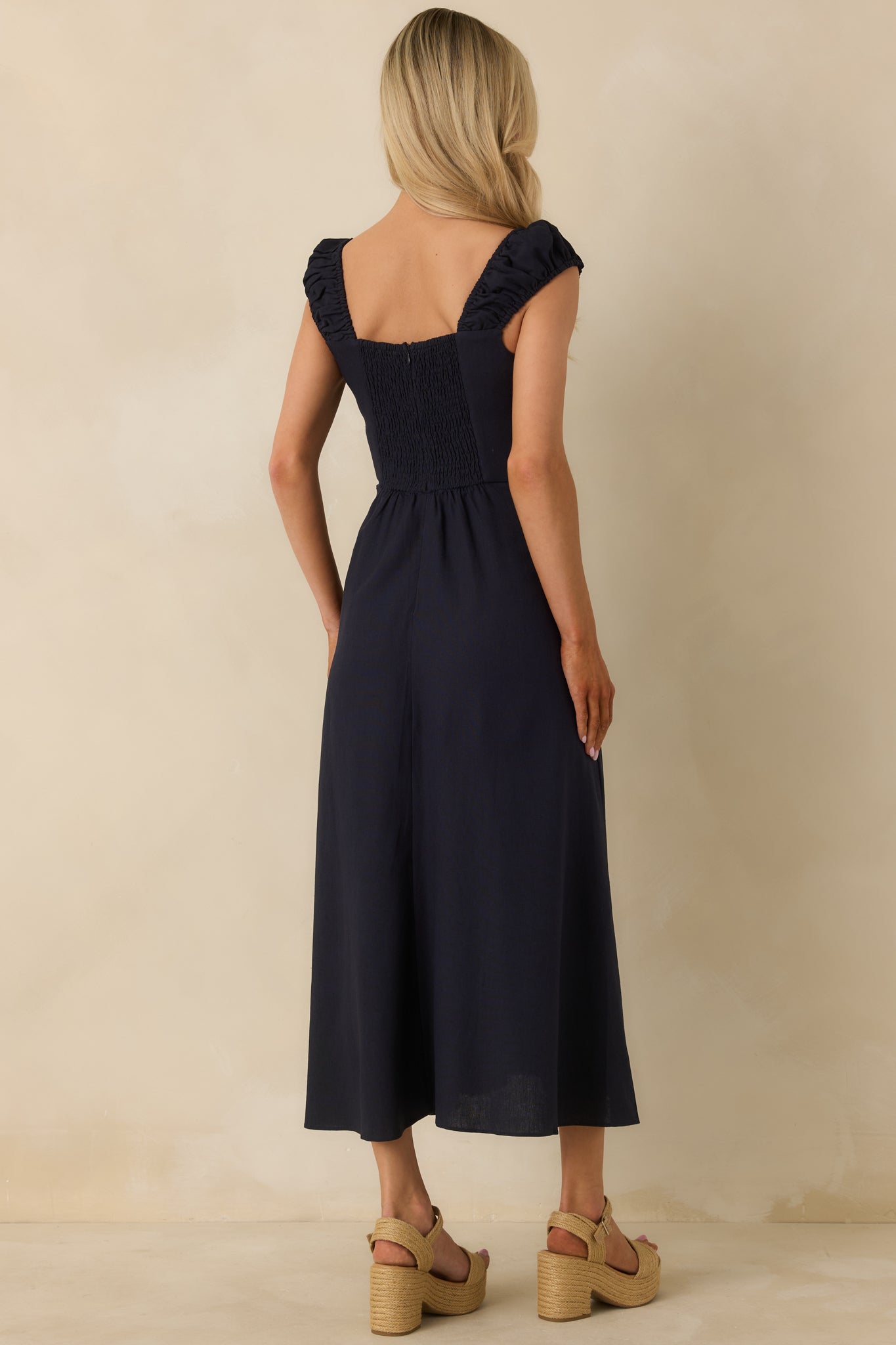 Back view of navy midi dress showing smocked back panel and hidden zipper closure.
