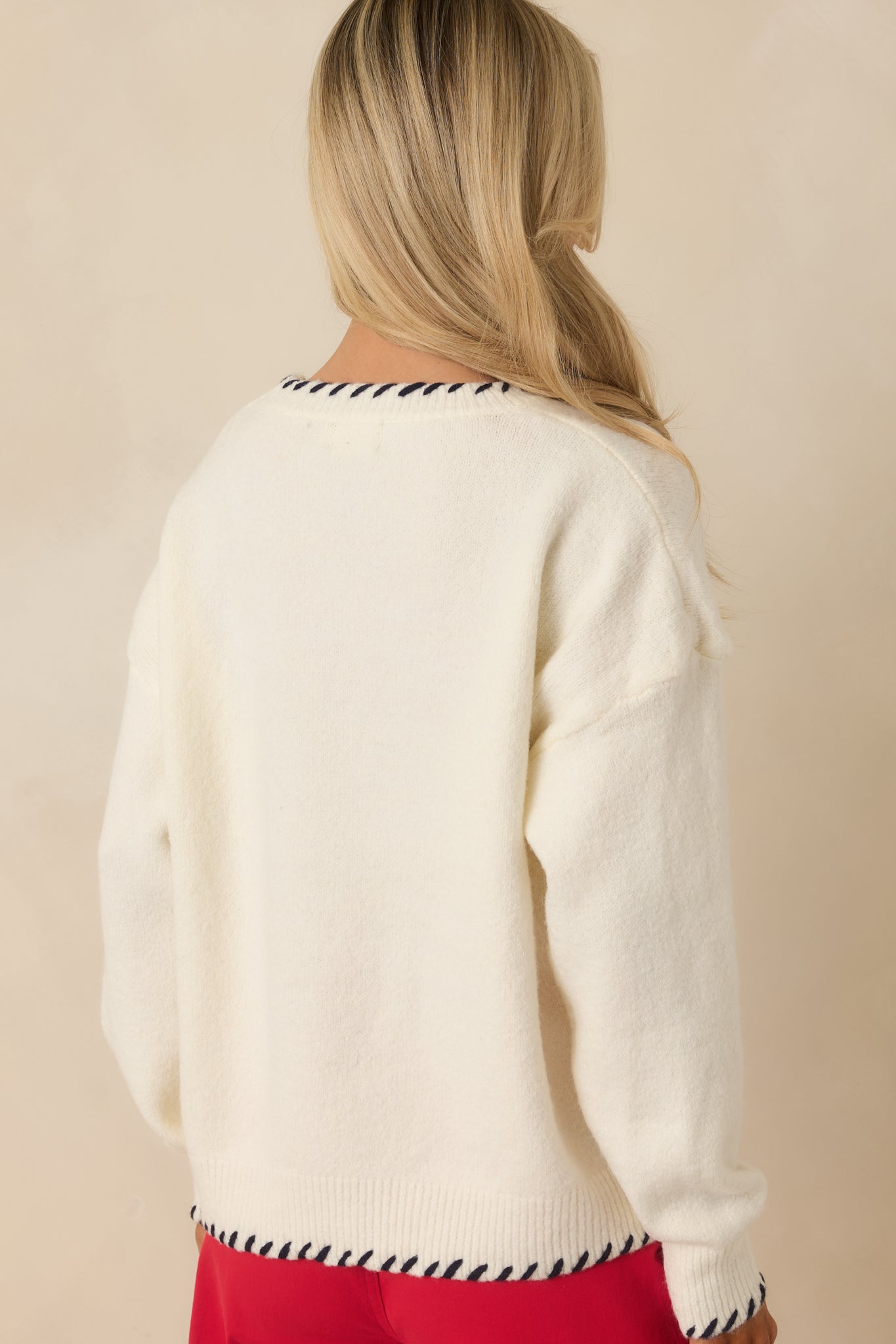 Rear view of the ivory multi knit sweater showing a smooth knit finish, relaxed fit, and contrast whipstitch detailing along the hem and cuffs.