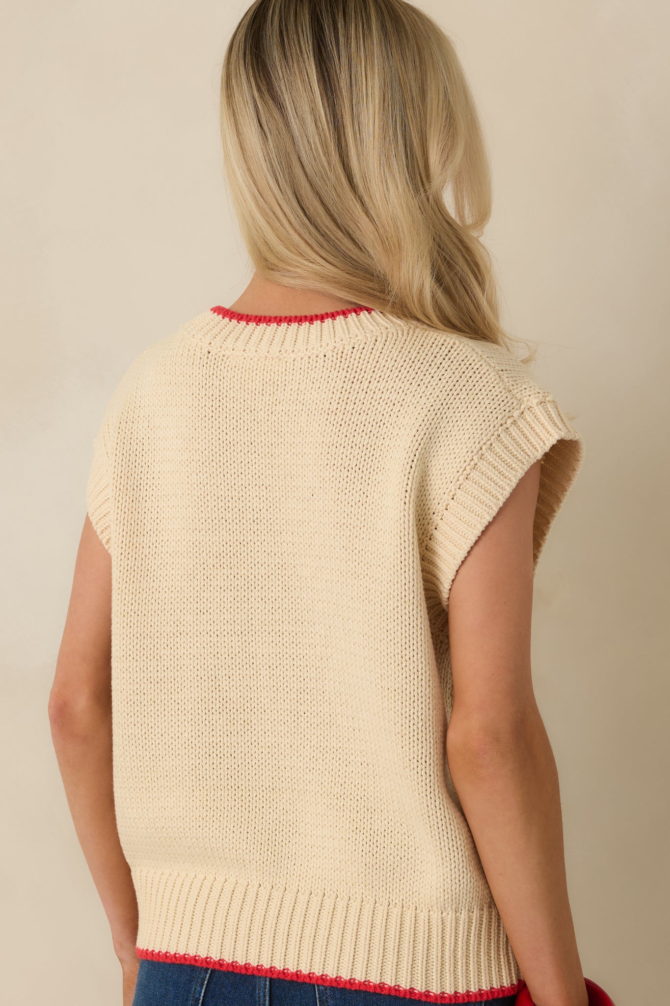 Back view of the ivory sleeveless sweater highlighting the smooth knit fabric, ribbed hem, and relaxed silhouette.