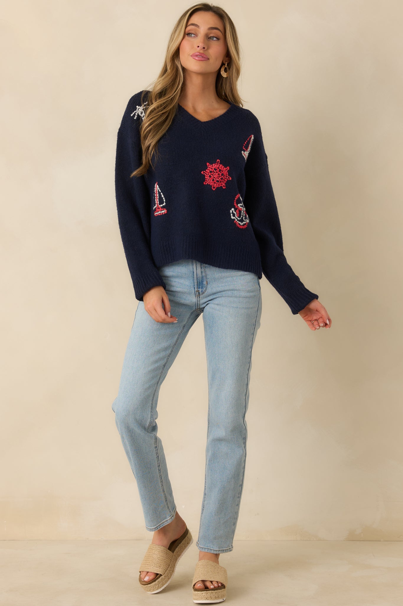 Navy long-sleeve sweater highlighting multi-color nautical embroidery over a comfortable, easy drape knit fabric.