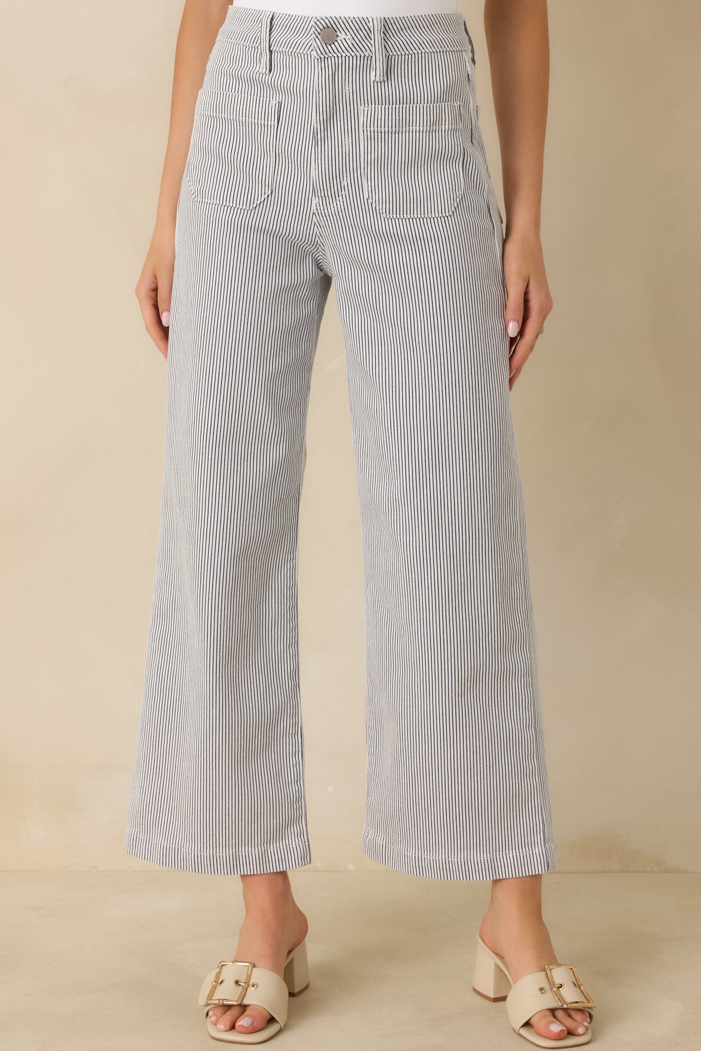 Cropped front view focusing on the high-rise waistband, zip fly, and belt loops of the navy stripe jeans.