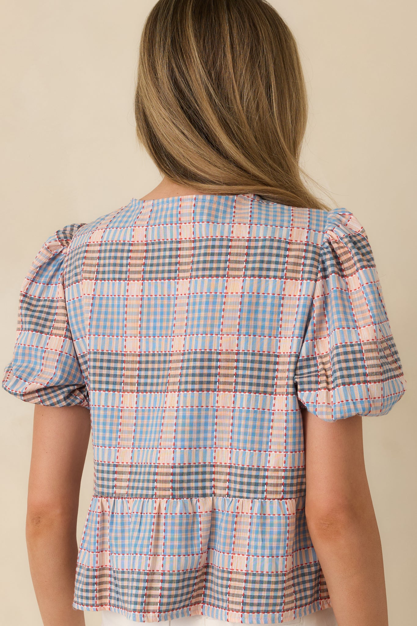 Blue multi plaid cotton top showing the rear neckline, short puff sleeves, and peplum hem shape.