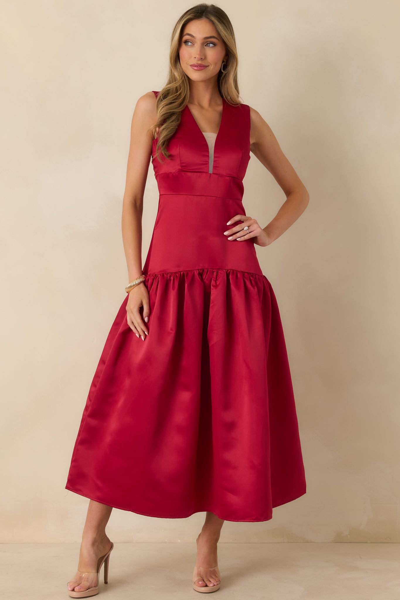 Shiny red maxi dress showcasing a fitted bodice with princess seams, deep V-neck with sheer mesh, and a gathered skirt falling from the drop waist.