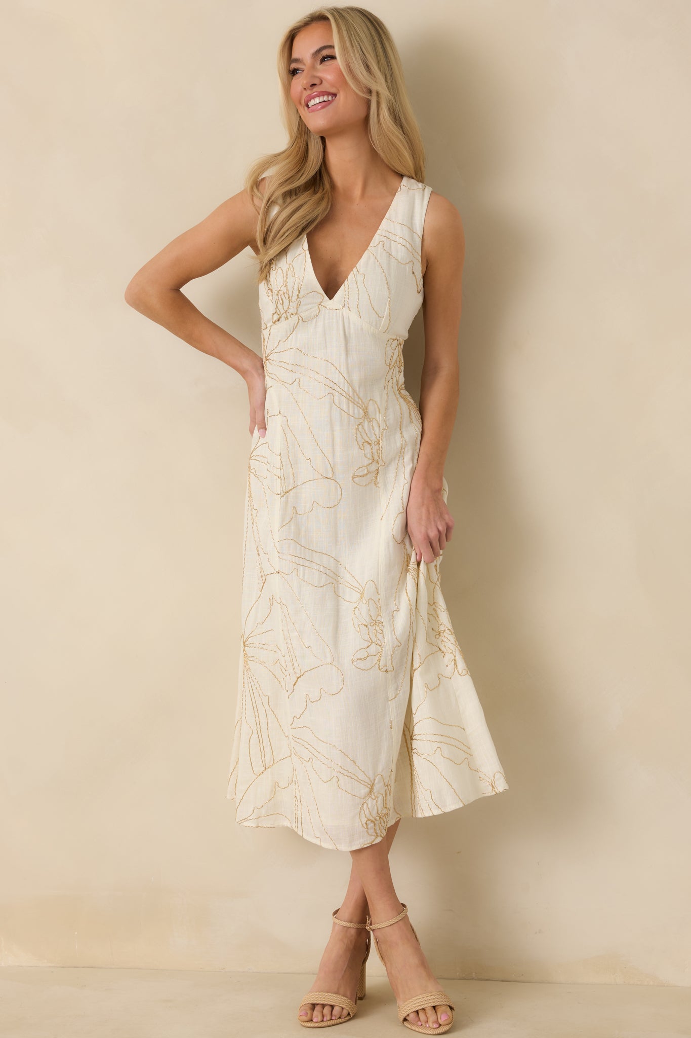 Ivory midi dress with golden beaded floral embroidery, a deep V-neckline, fitted bodice, and a flowy skirt falling to mid-calf.
