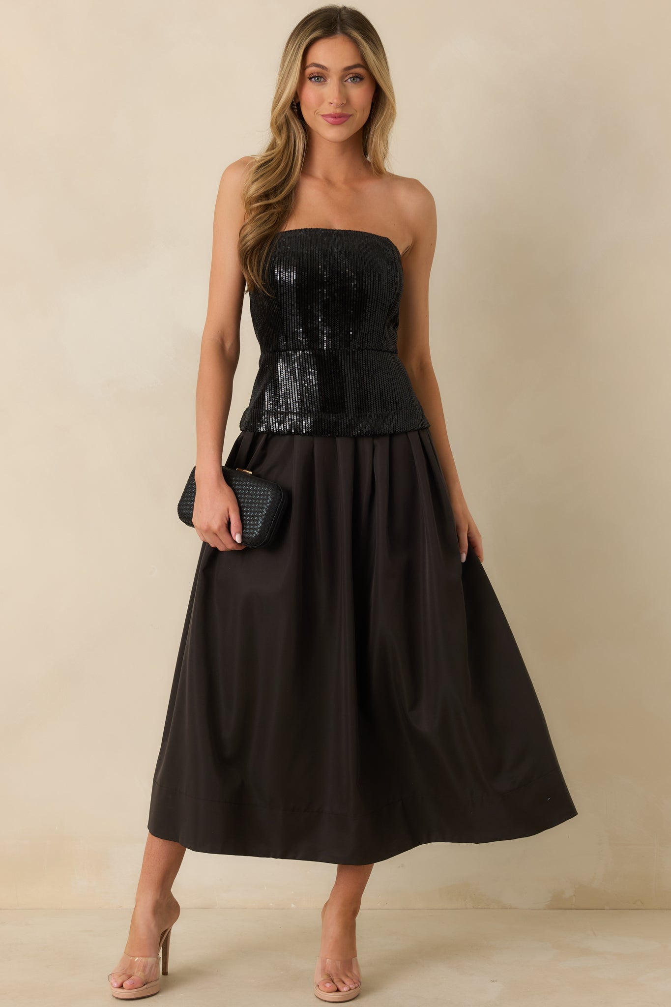 Black midi dress with a strapless sequin bodice, structured with boning, and a voluminous pleated skirt creating a fit-and-flare silhouette.