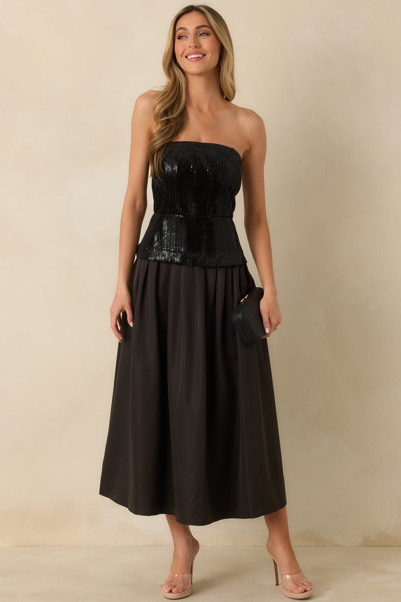 Black midi dress with a strapless sequin top, structured bodice, and pleated skirt that flares elegantly from the waist.