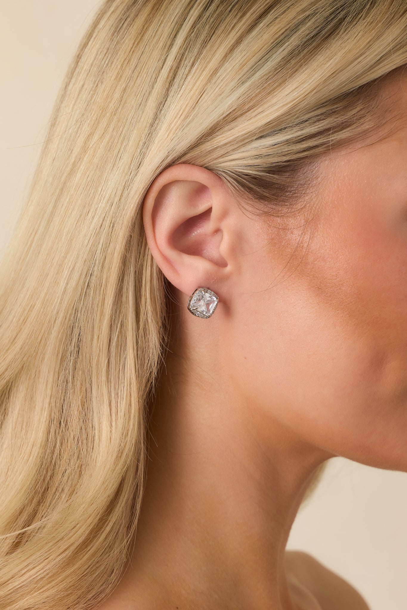 Silver stud earrings with faceted cushion-cut cubic zirconia centers, framed by a sparkling pavé halo and finished with polished metal settings.