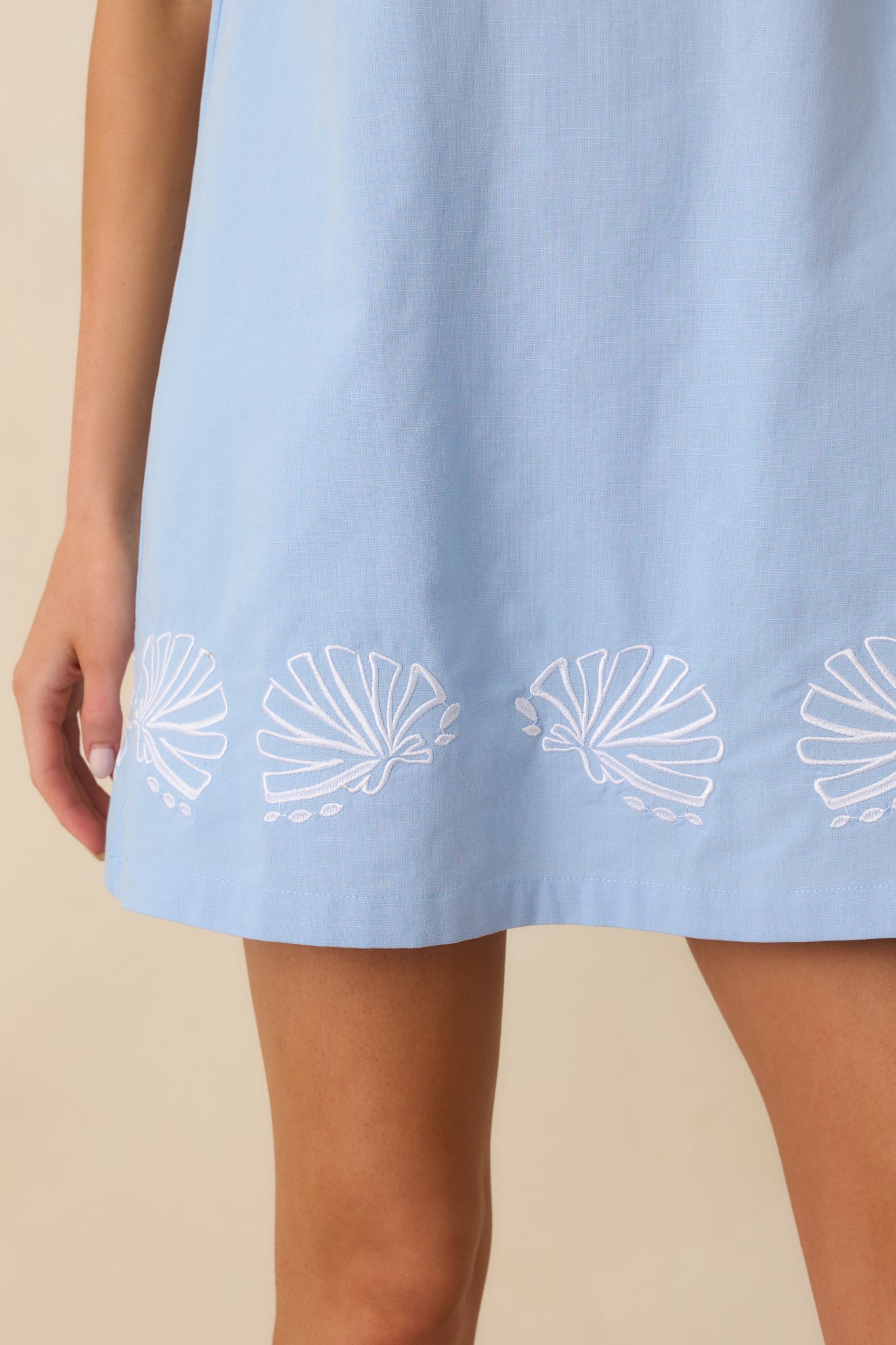 Detailed close-up of the embroidered shell motifs along the hem and smooth cotton-blend texture.