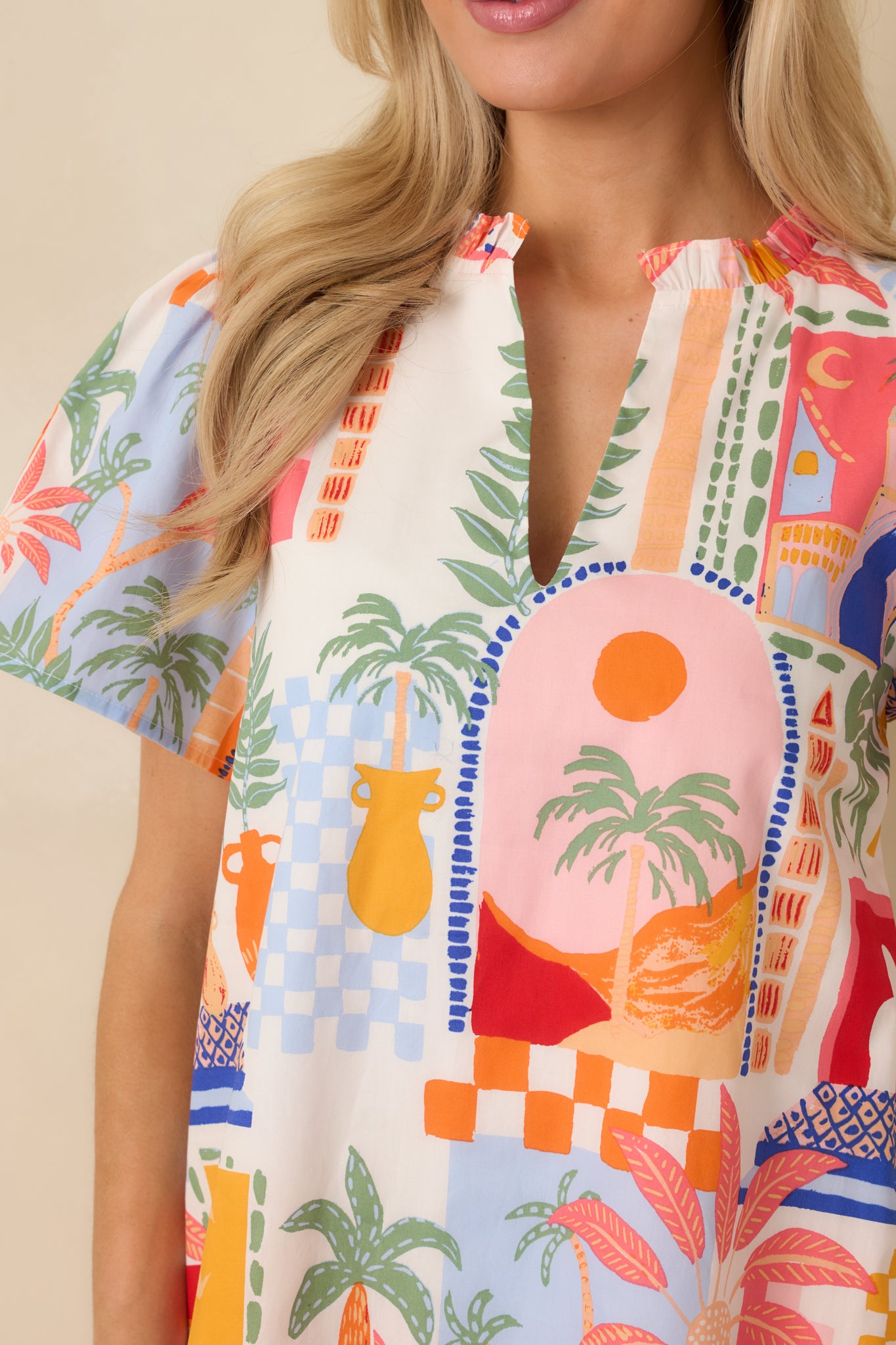 Close-up of the orange and pink mini dress showing the flutter sleeves, notched V-neckline, and ruffle hem detailing.