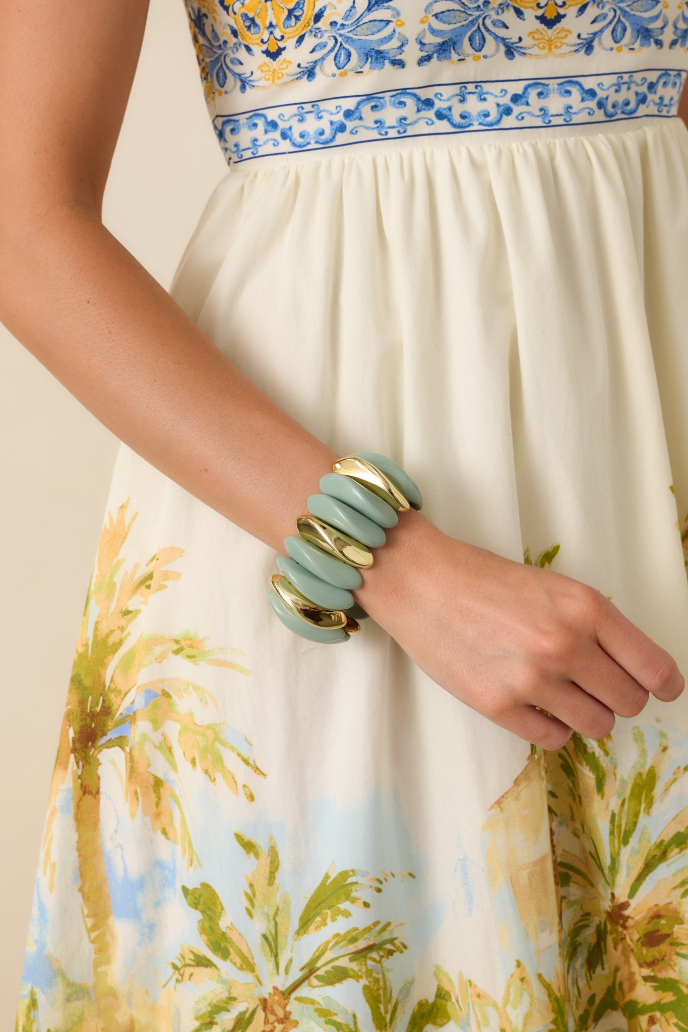 Sage green stretch bracelet featuring sculptural contoured links with polished gold accent details.