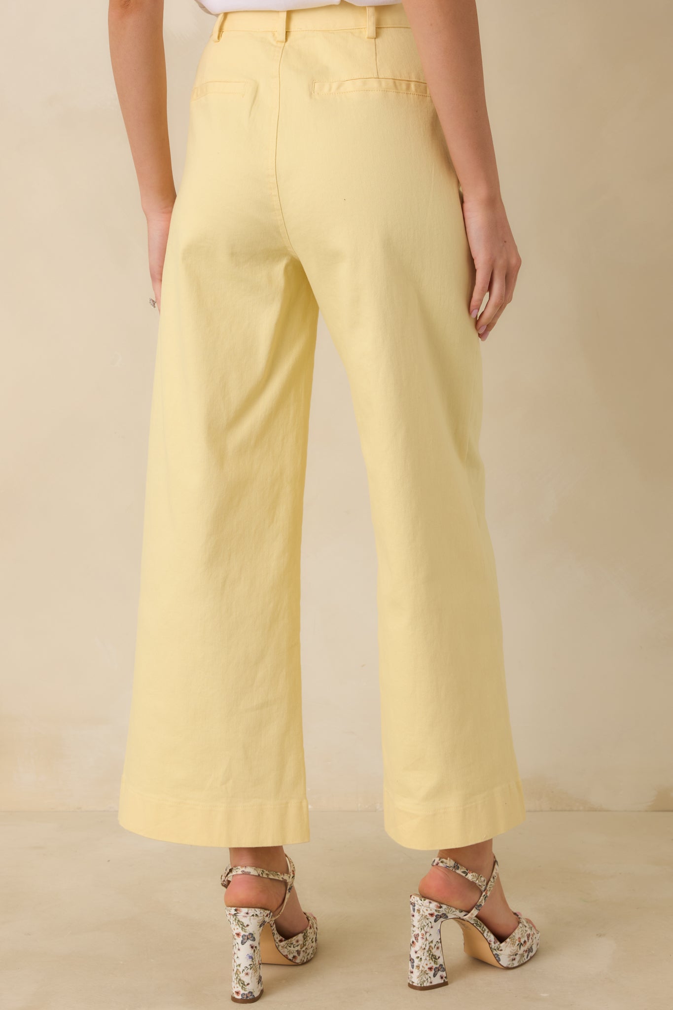 Rear view of yellow pants showing structured back welt pockets and smooth wide leg drape.