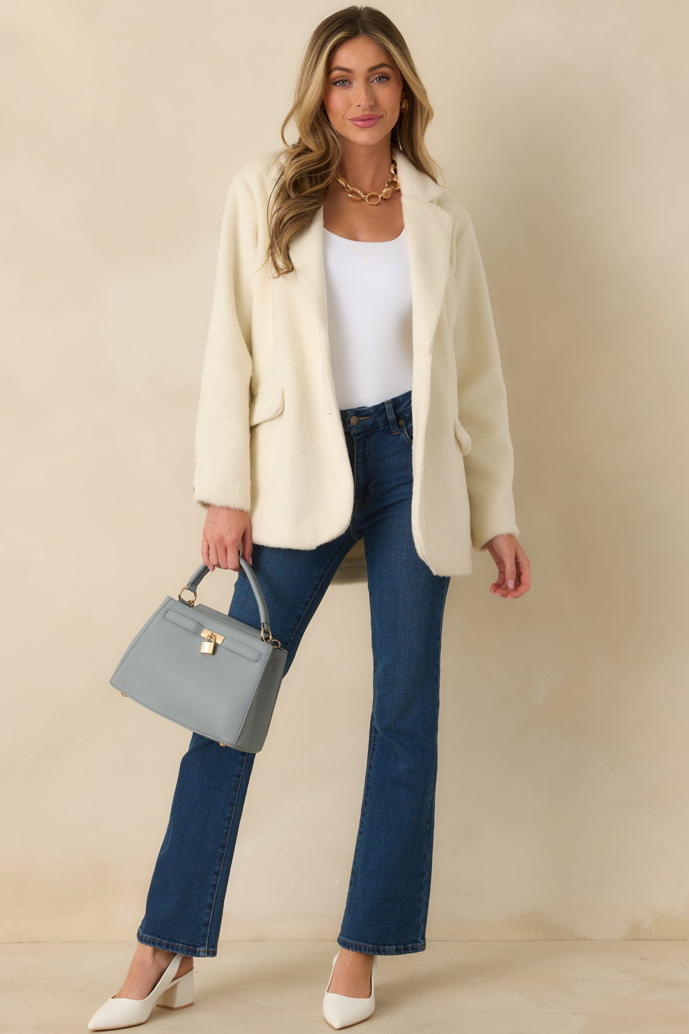Front view of relaxed yet tailored ivory blazer featuring long sleeves and flap pockets.