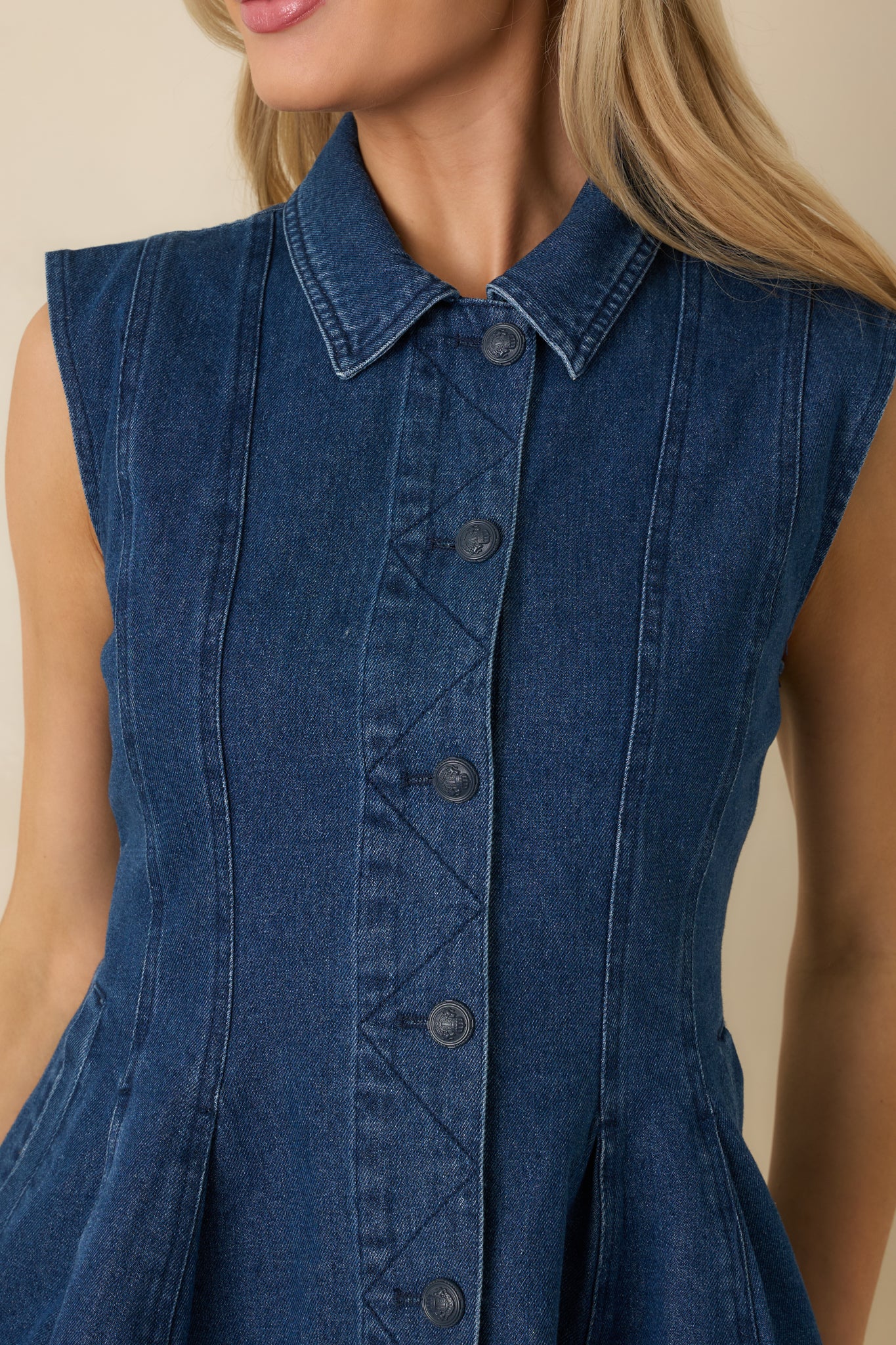 Close view of the dark wash cotton denim top showcasing the front button hardware and precise seam stitching.