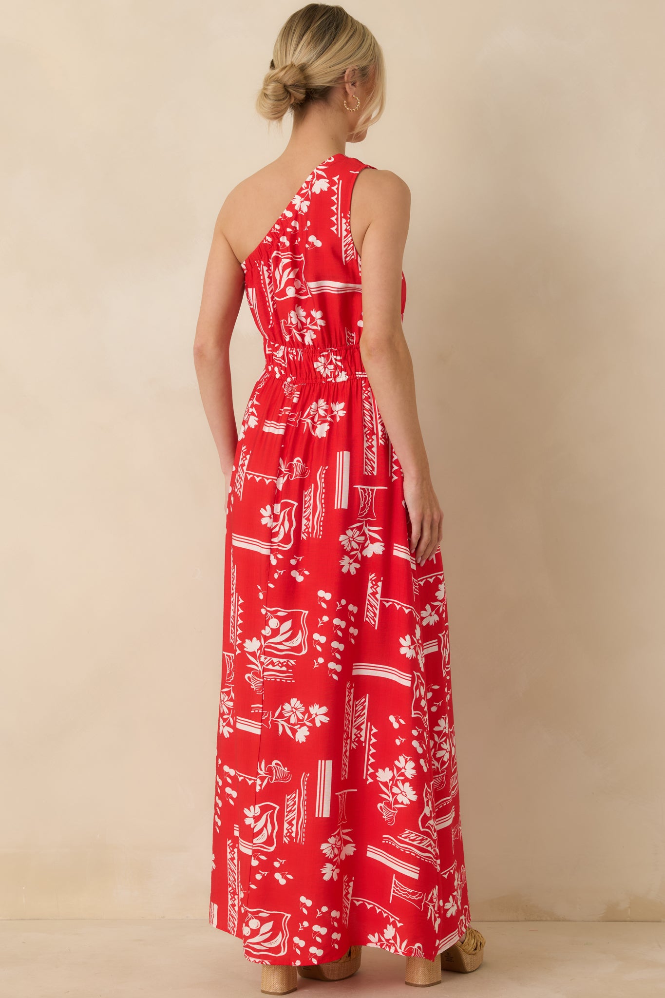 Back view of red maxi dress highlighting the elastic waist, full-length hem, and printed fabric.