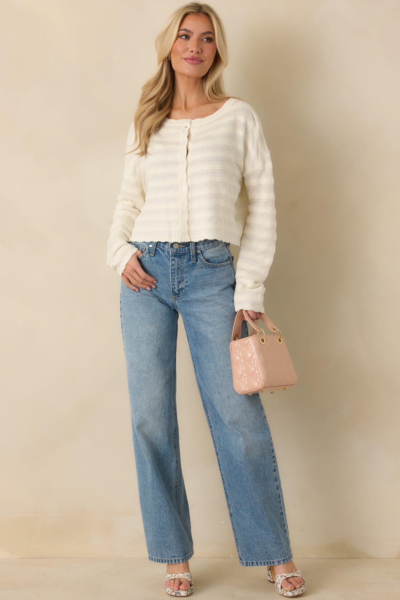 Ivory textured knit cardigan with a button-front closure, long sleeves, and softly scalloped neckline and hem.