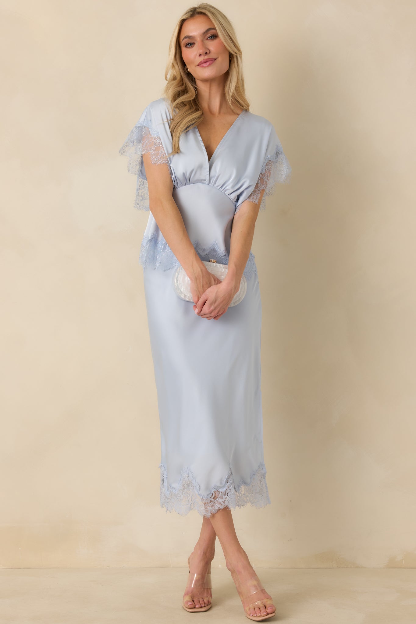 Full-length image showing the powder blue blouse’s relaxed silhouette and fluid drape, featuring lace-trimmed flutter sleeves.