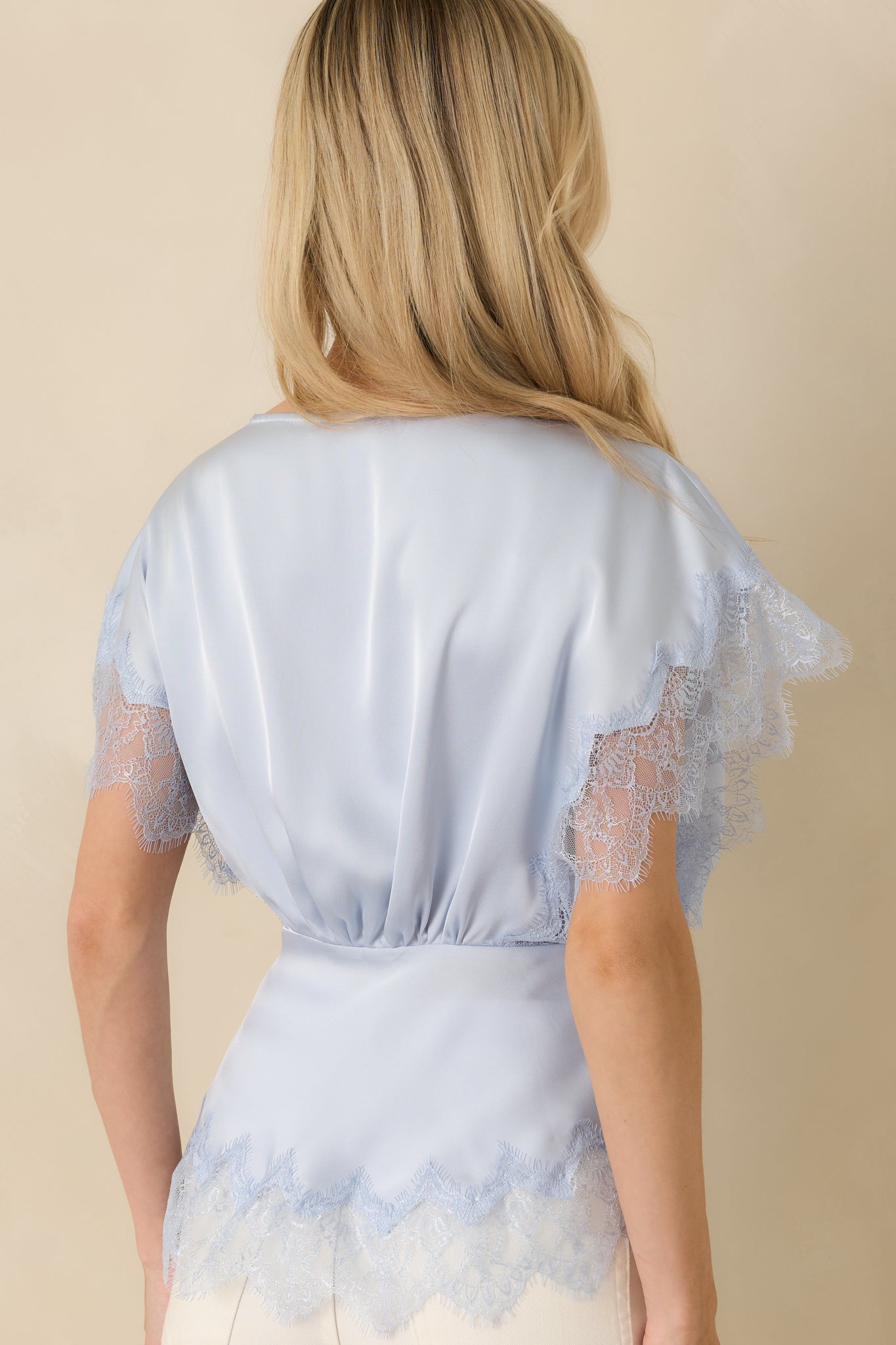 Back view of the powder blue blouse showing smooth woven fabric and relaxed silhouette without visible fastenings.