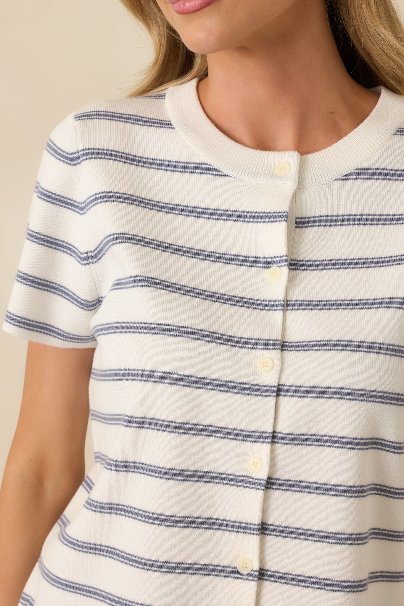 Close-up of ribbed knit fabric showing horizontal navy stripes, fine rib texture, and button-front closure.
