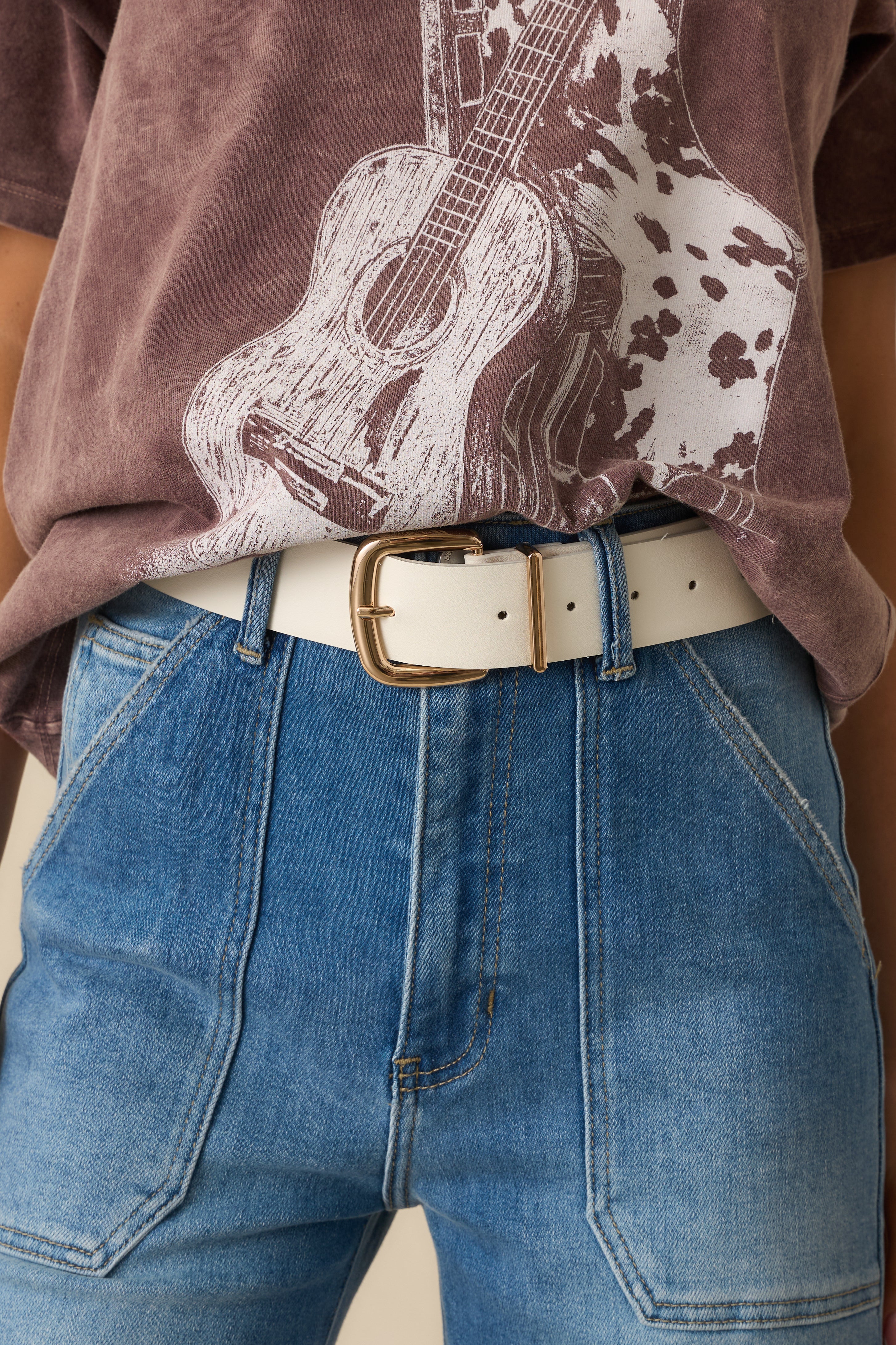 Cropped view showing the white faux leather belt with gold-tone square buckle and stitched edges.