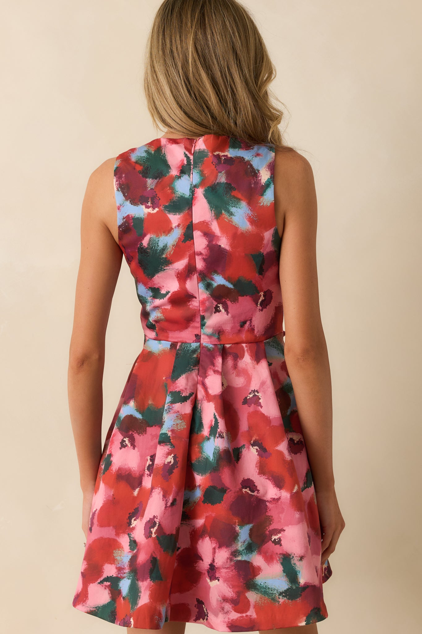 Rear view of the floral mini dress showing the concealed zipper and softly flared pleated skirt.