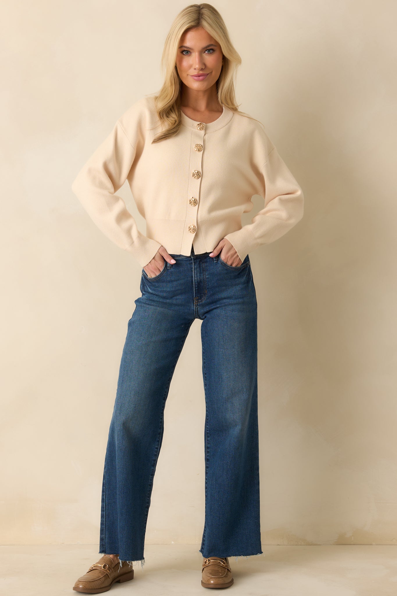 Front view of ecru beige cardigan featuring gold flower-shaped button closures, crew neckline, and long sleeves.