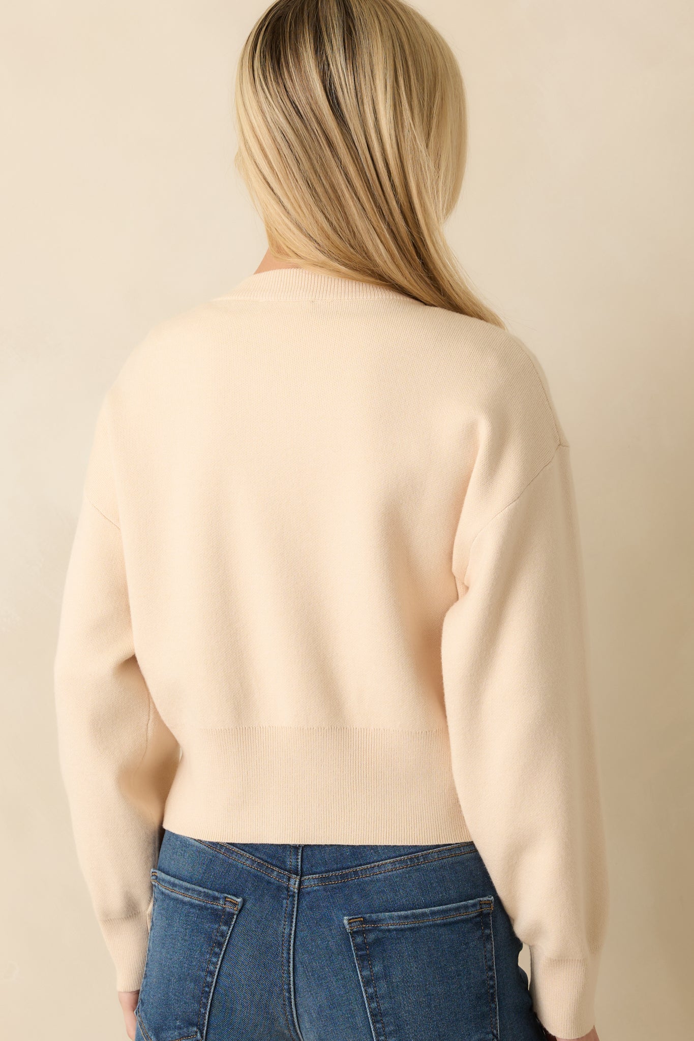 Back view of the cardigan showing long sleeves, ribbed waistband, and smooth knit back panel.