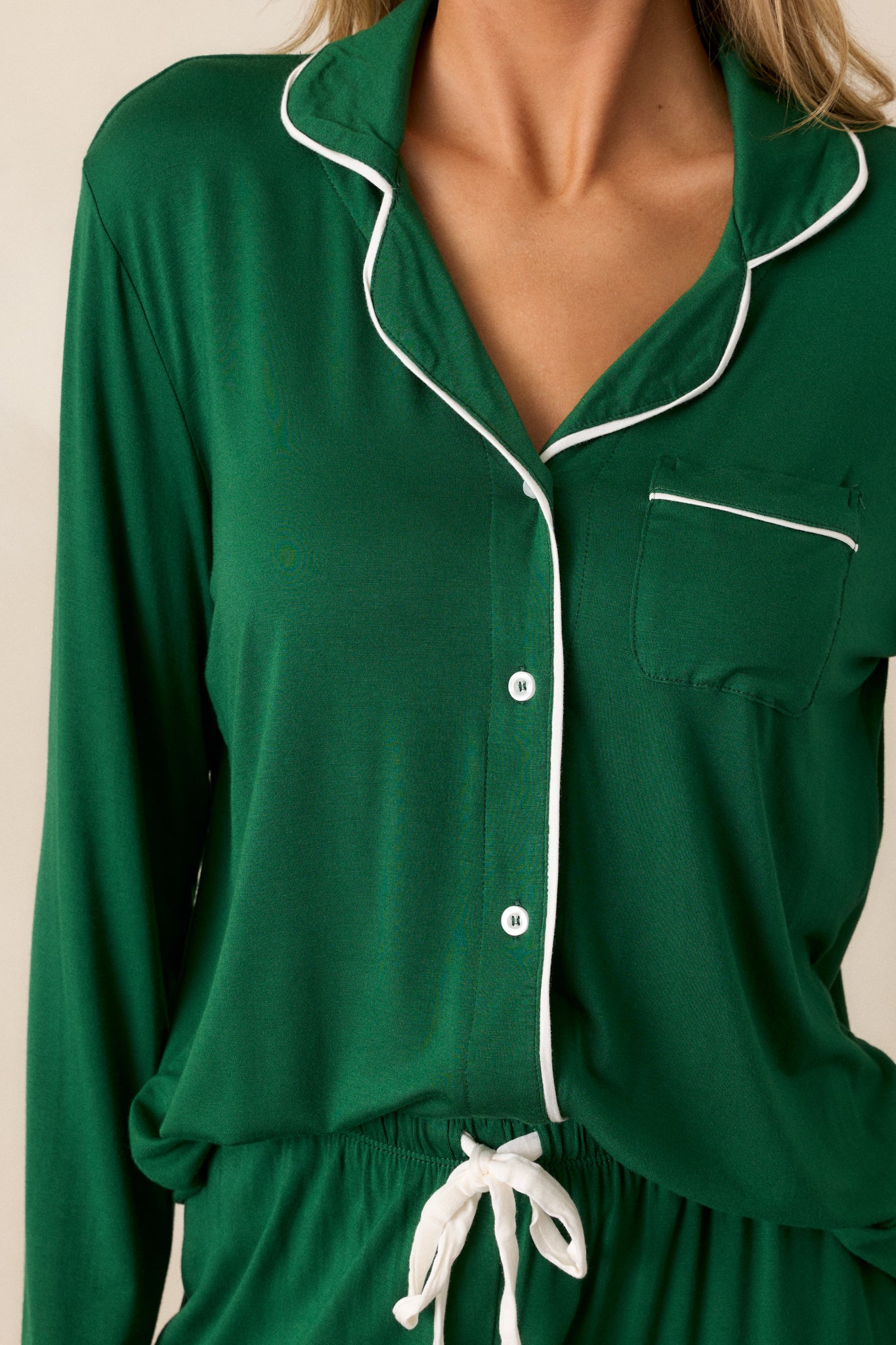 A zoomed-in shot of the button front and white trim, showing the texture of the green fabric and the fine white edging along the collar and buttons.