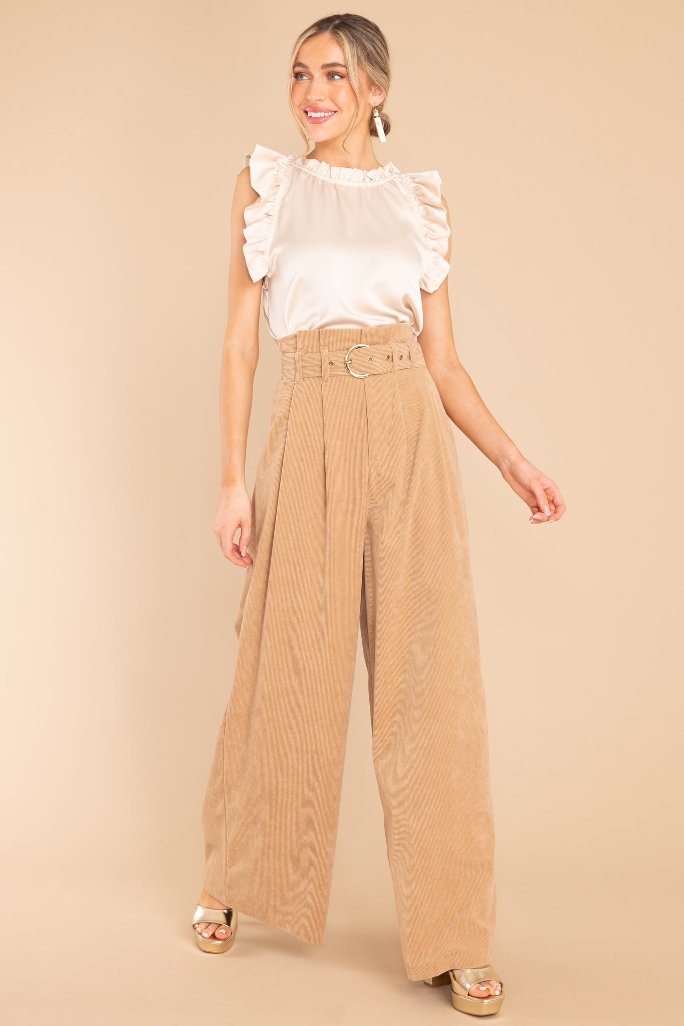 This champagne colored top features a ruffled neckline, ruffled sleeves, a satin-like material throughout, and a keyhole button detail in the back.