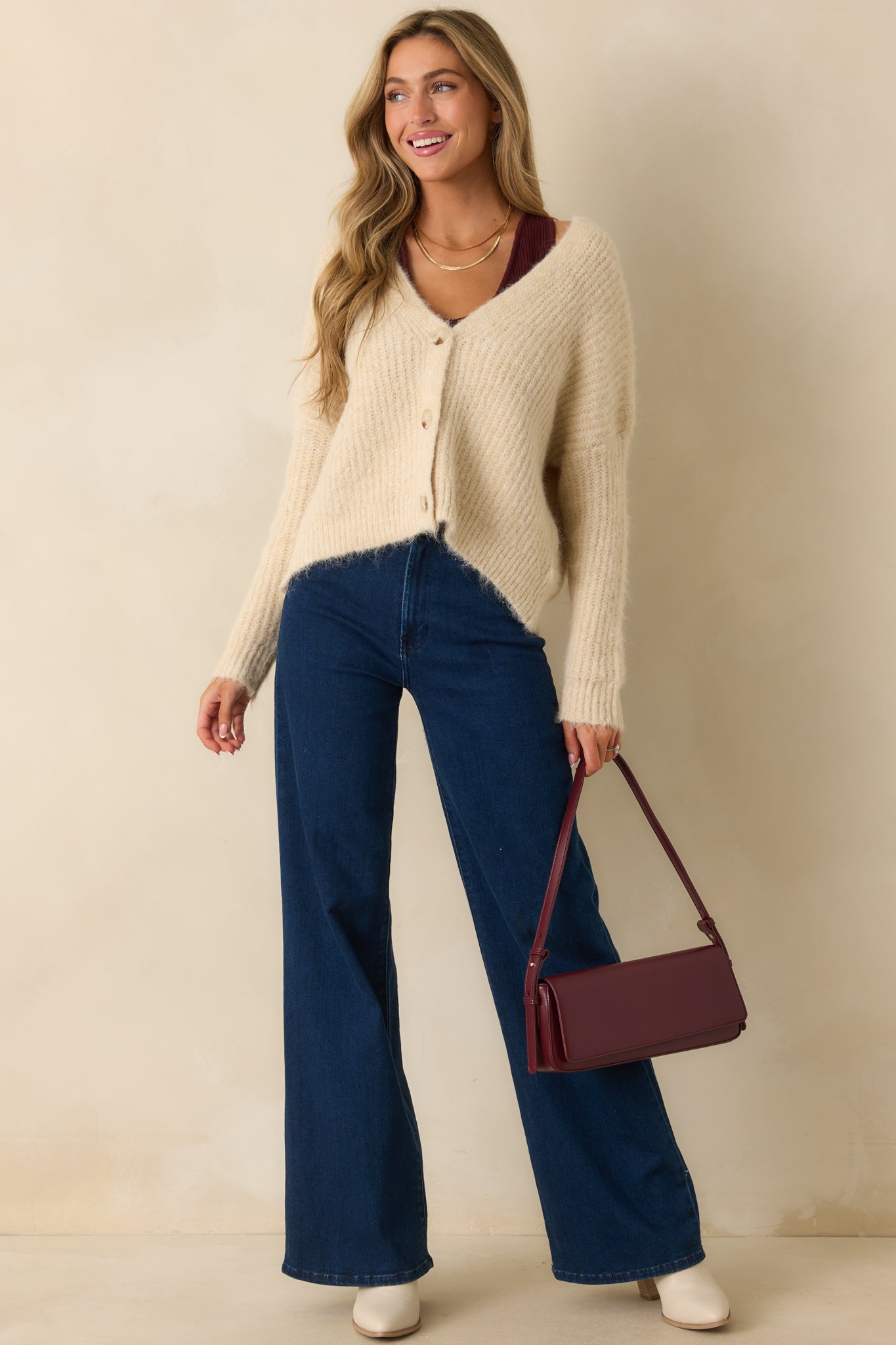 Front-facing full body view of an ivory cardigan with a deep V-neckline, long sleeves, and tortoise shell button closure.