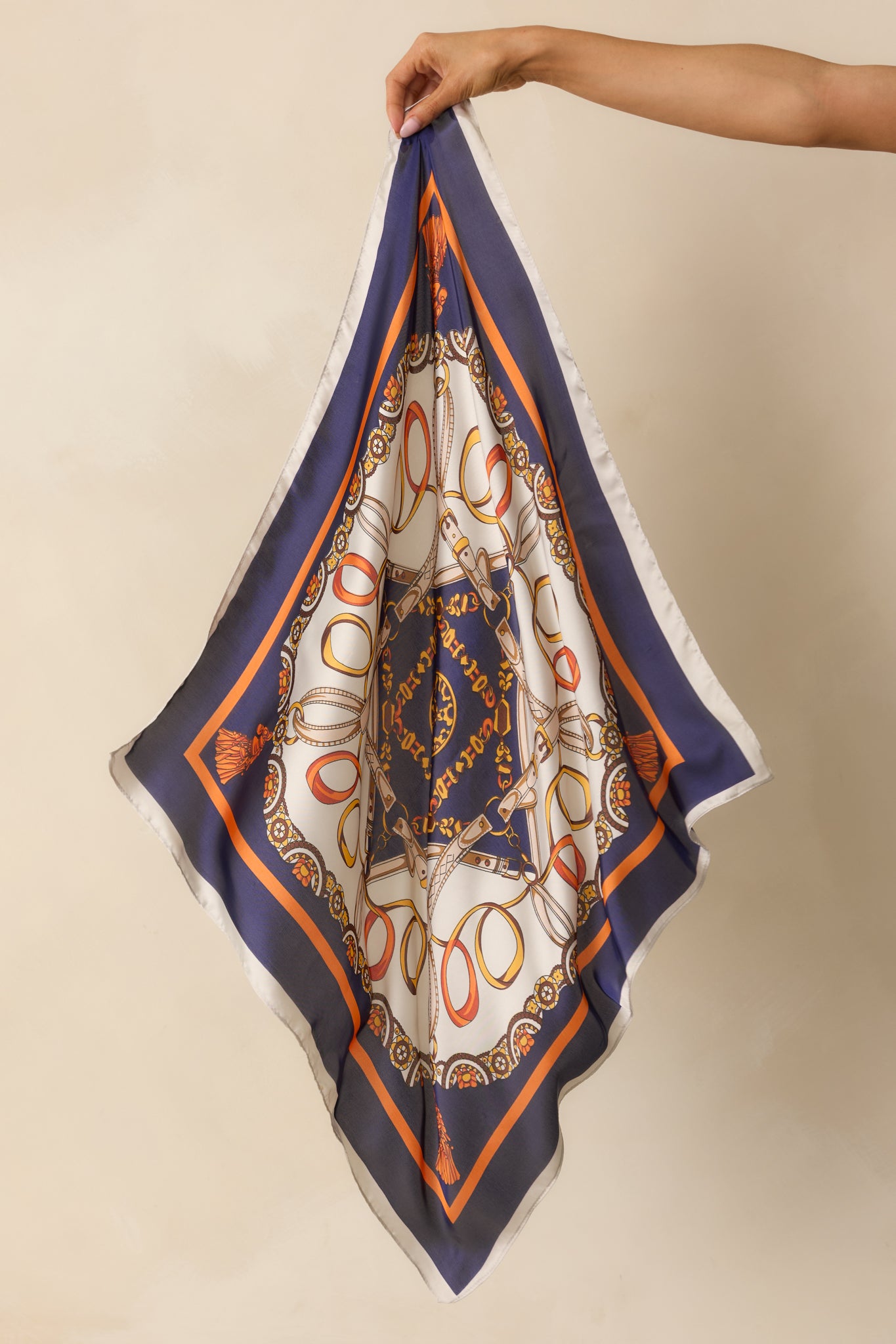 Elegant navy scarf laid out to reveal its full pattern of colorful chains and tassels framed by a bold gold and orange edge.
