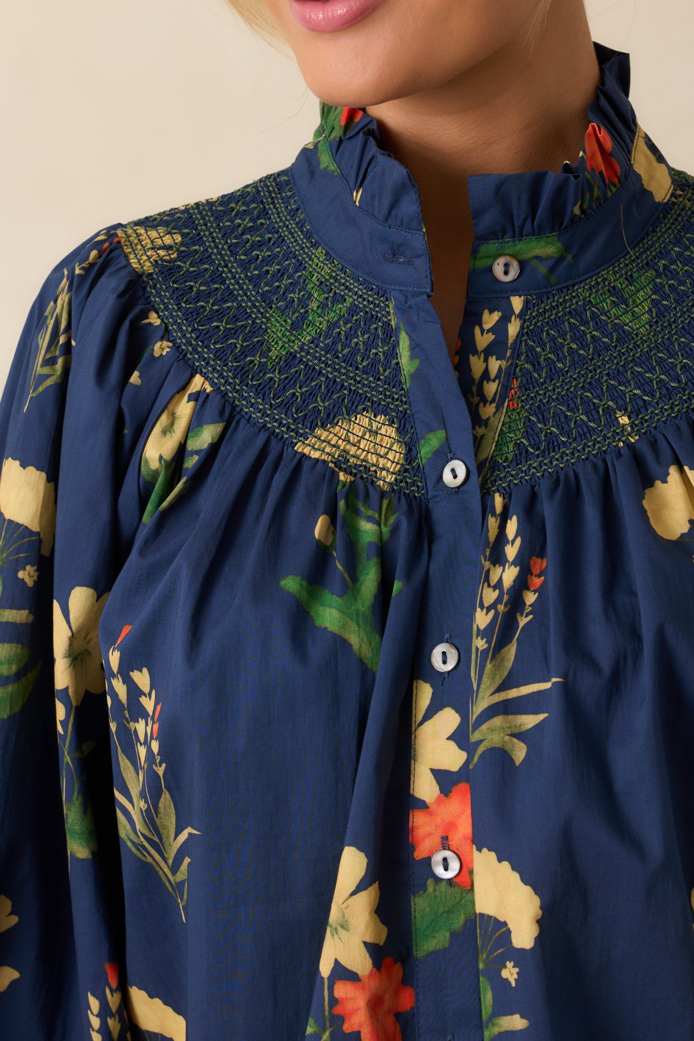 Detailed shot showing the smocked yoke, embroidery, and ruffled collar of the blouse.