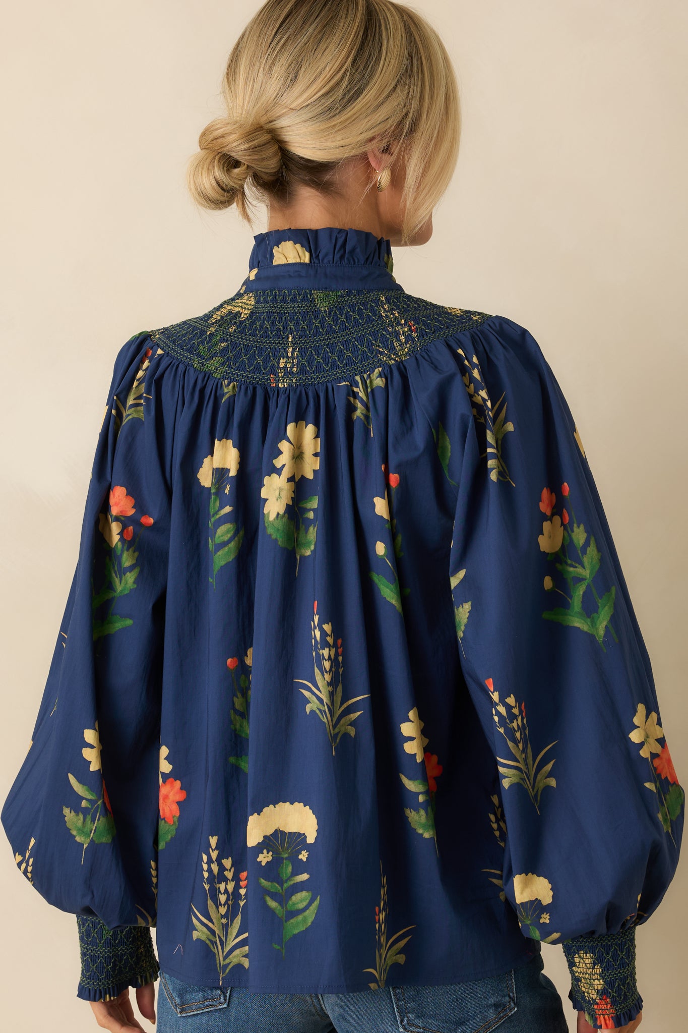 Rear view of the navy floral blouse displaying the smooth back and long bishop sleeves.